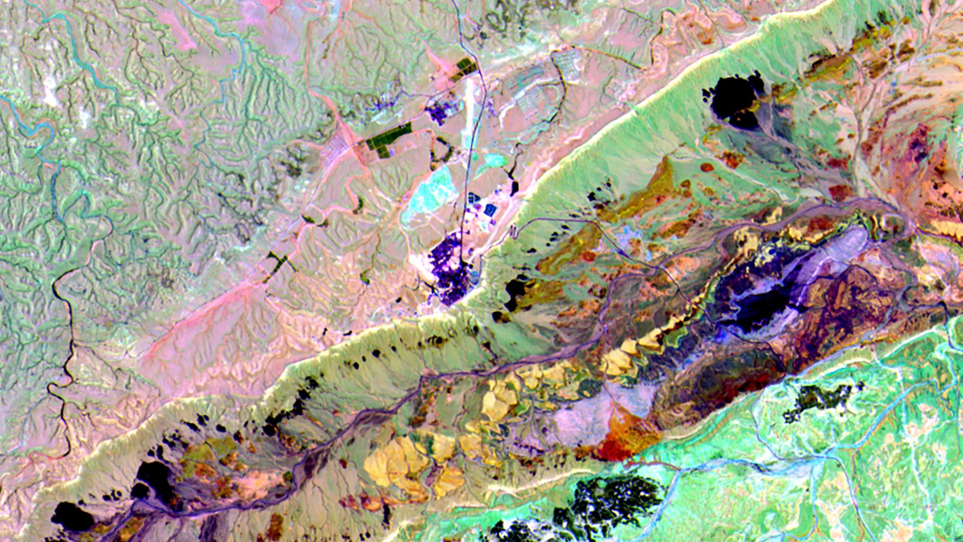Satellitenaufnahme eines Kraters. Verschiedene Gesteinsarten sind unterschielich gefärbt.