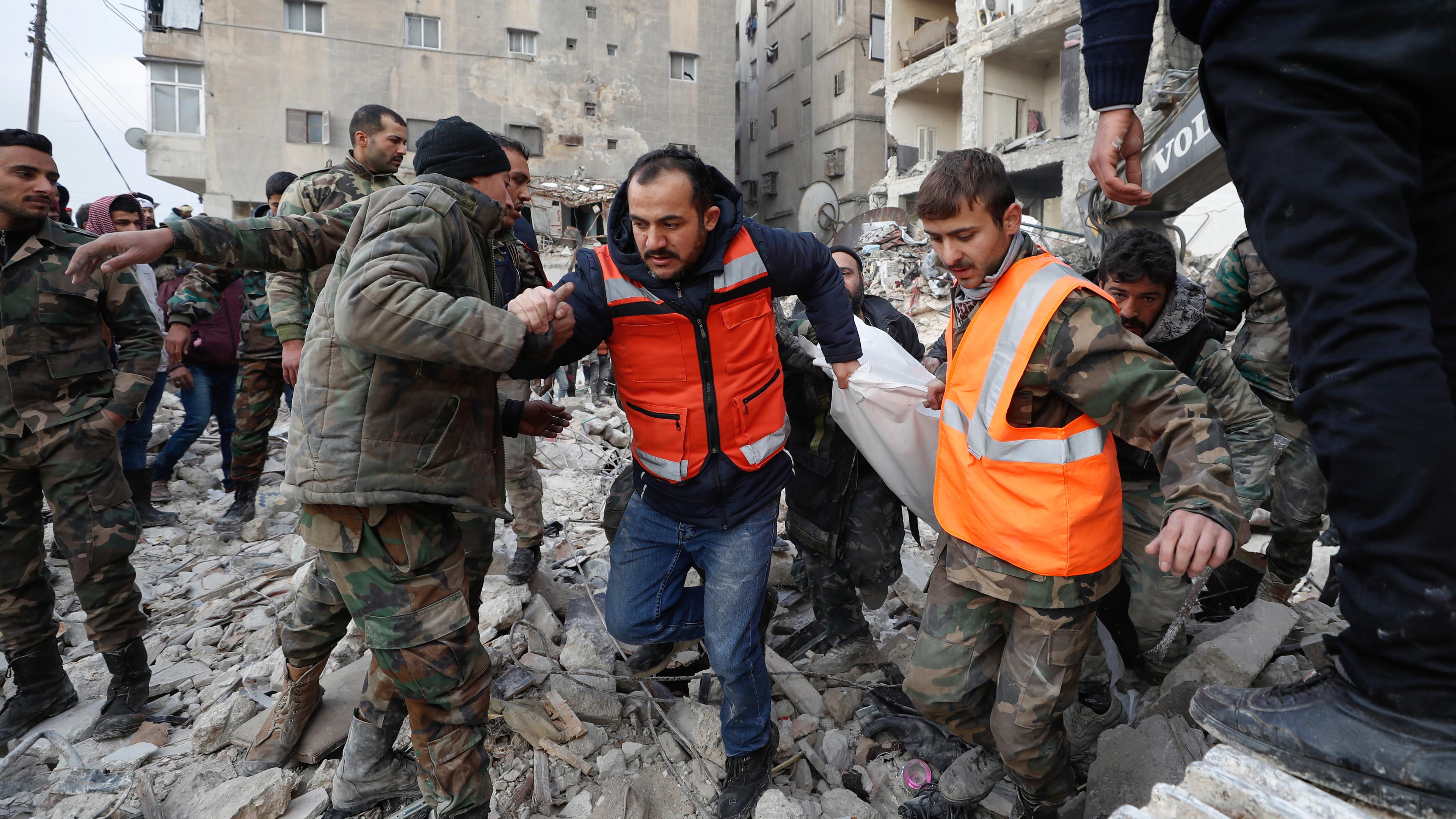 Mitarbeiter des syrischen Zivilschutzes und Sicherheitskräfte durchsuchen die Trümmer eingestürzter Gebäude in Aleppo, aufgenommen am 07.02.2023 