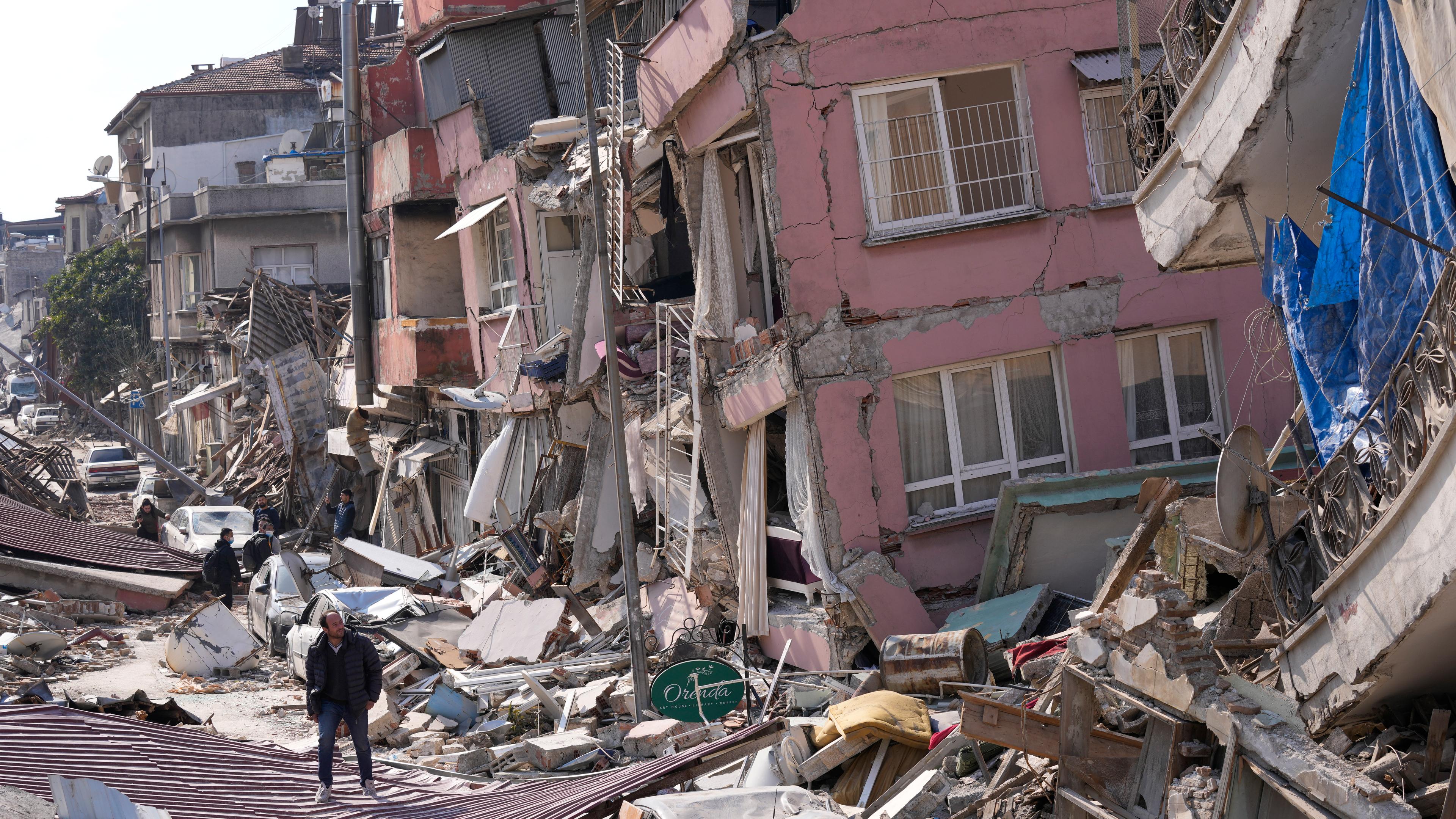 Ein Mann geht über die Trümmer eingestürzter Gebäude. Die Zahl der Toten nach den Erdbeben im türkisch-syrischen Grenzgebiet ist auf mehr als 25 000 gestiegen.