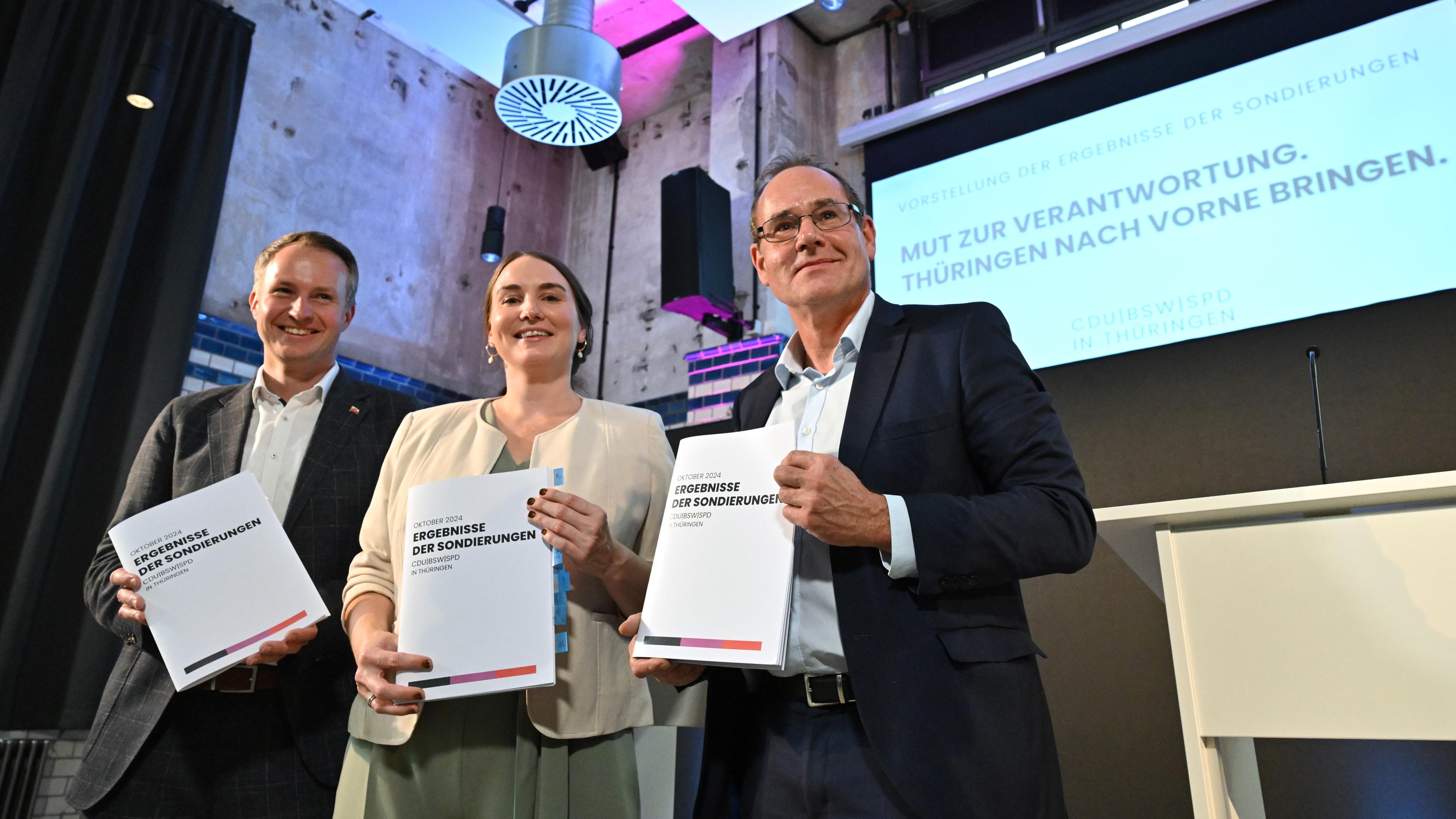 Thüringen, Erfurt: Andreas Bühl (l-r, CDU), Katharina Schenk (SPD) und Tilo Kummer (BSW) präsentieren eine Druckschrift mit den Ergebnissen der Sondierungsgespräche zwischen CDU, BSW und SPD in der Erfurter Zentralheize.