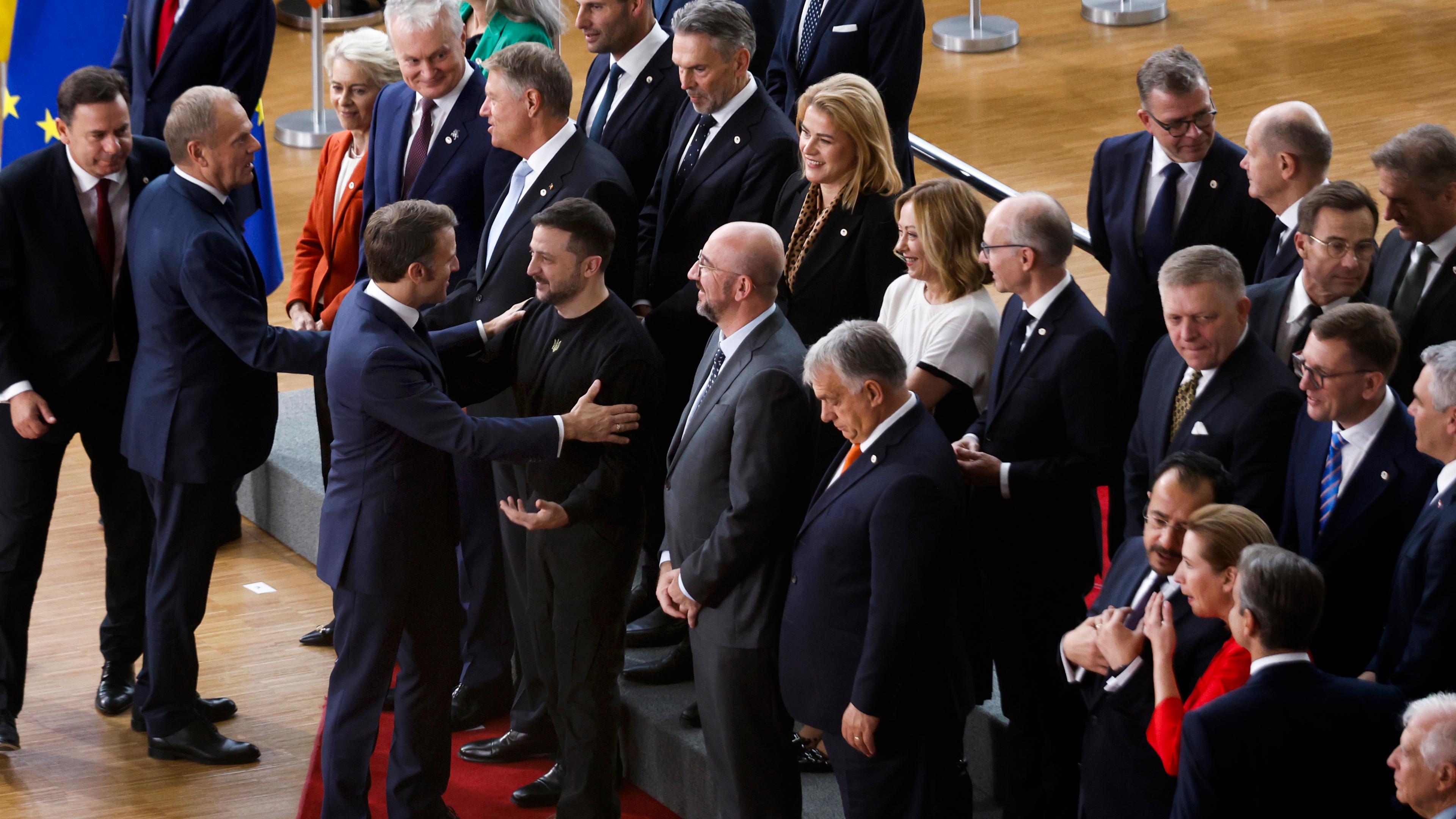 17.10.2024, Belgien, Brüssel: Der französische Präsident Emmanuel Macron (l) begrüßt den ukrainischen Präsidenten Wolodymyr Selenskyj, als sie mit den Staats- und Regierungschefs der EU für ein Gruppenfoto beim Eu-Gipfel in Brüssel aufstellen. 