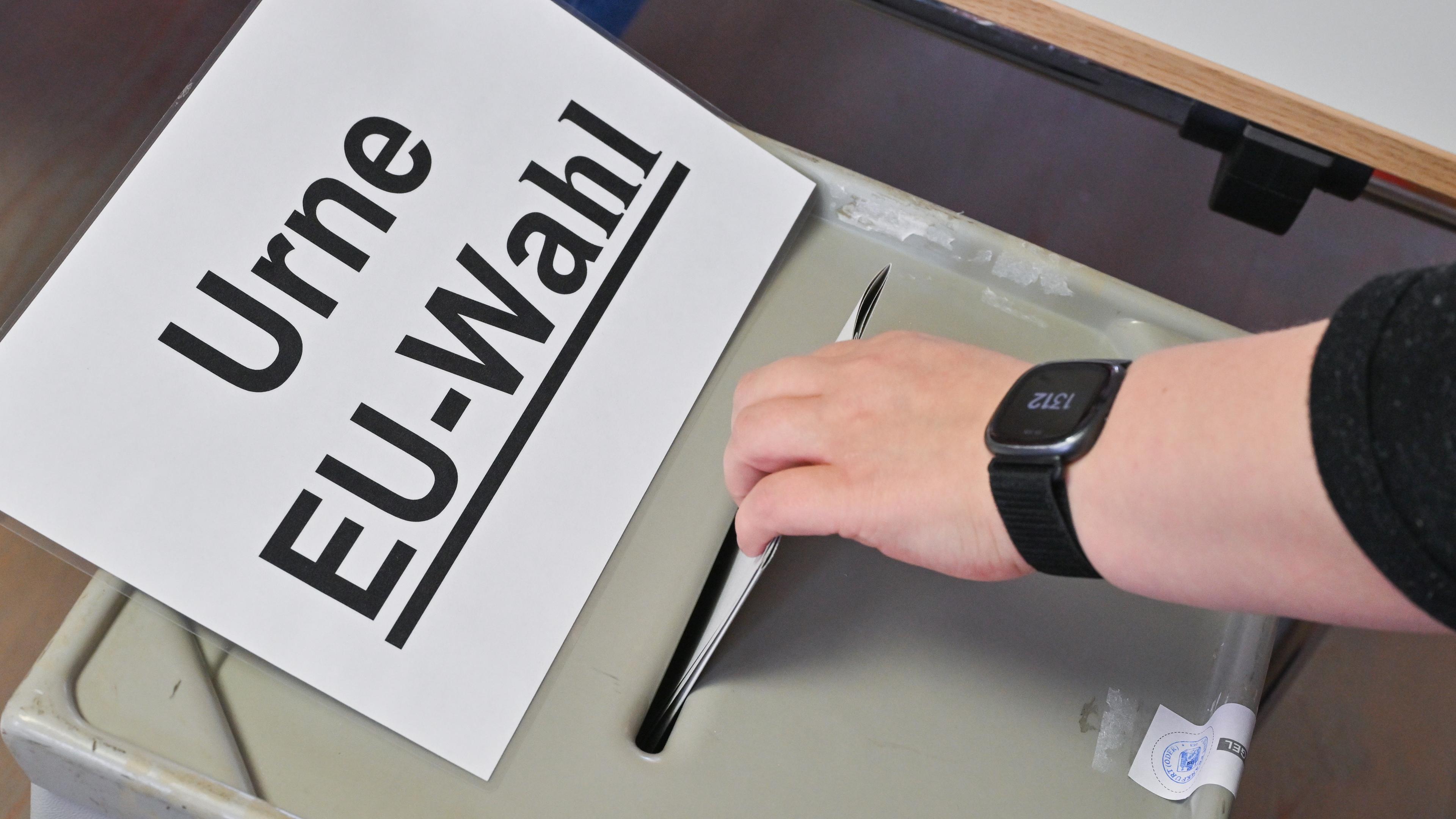 Eine Person steckt ihren Stimmzettel in eine Wahlurne mit der Aufschrift «Urne EU-Wahl»