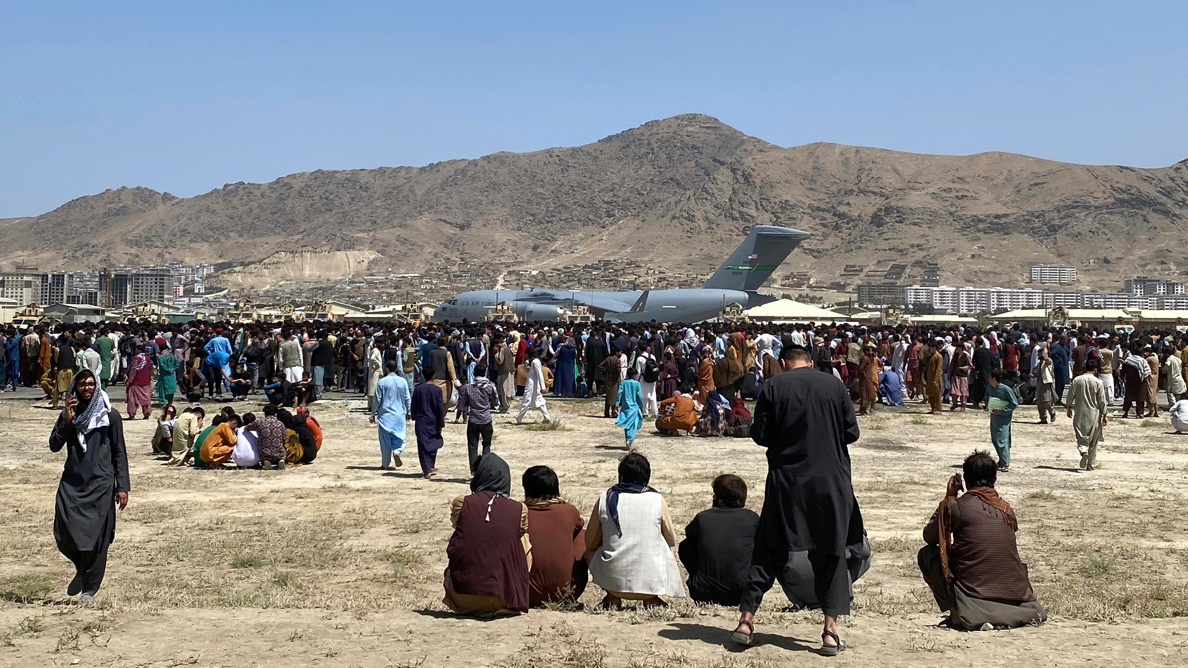 Afghanistan, Kabul: Hunderte von Menschen versammeln sich in der Nähe eines C-17-Transportflugzeugs der US-Luftwaffe an einer Absperrung des internationalen Flughafens. 