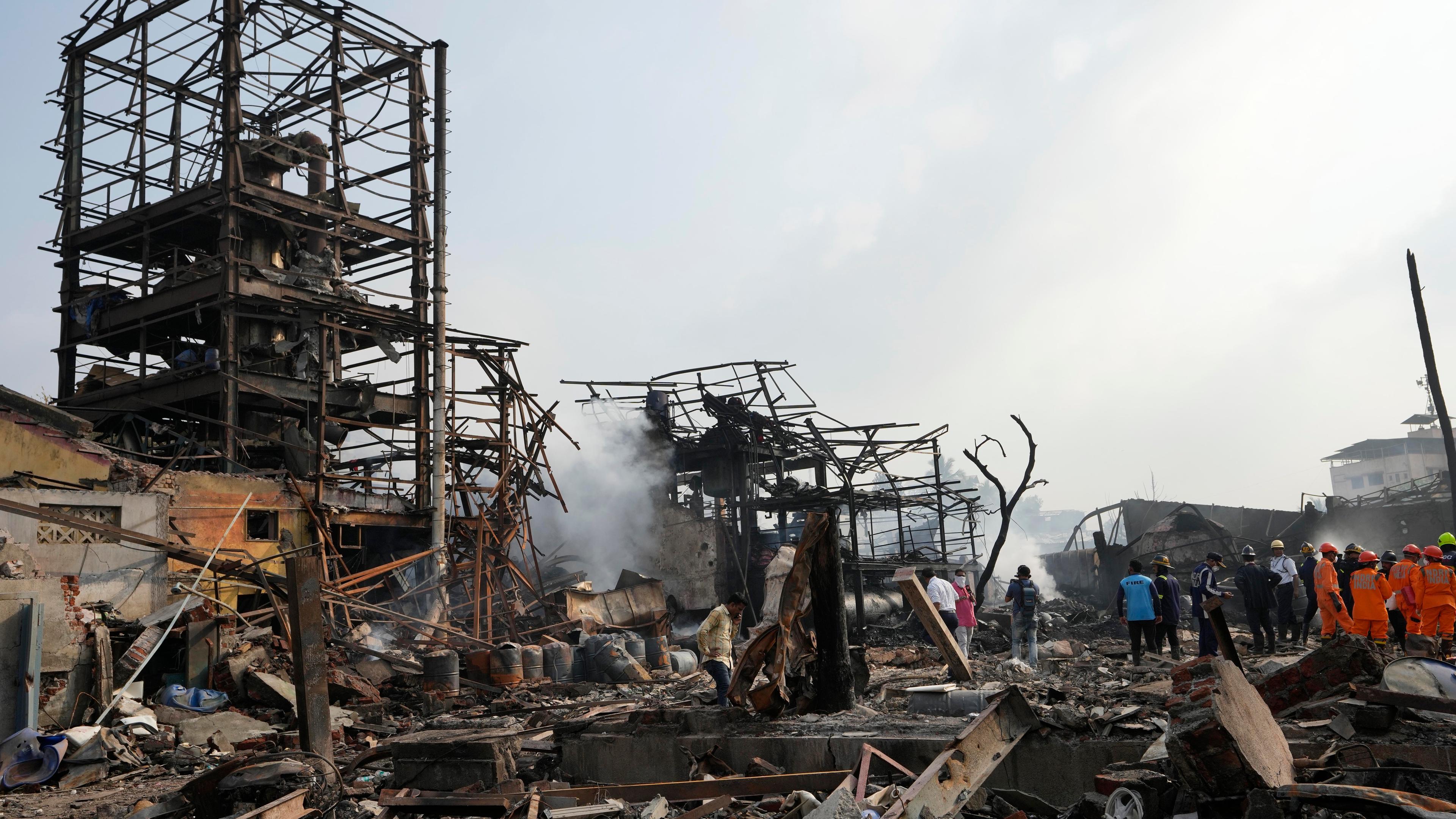 Eine Fabrik liegt in Trümmern, am Rand stehen Rettungskräfte