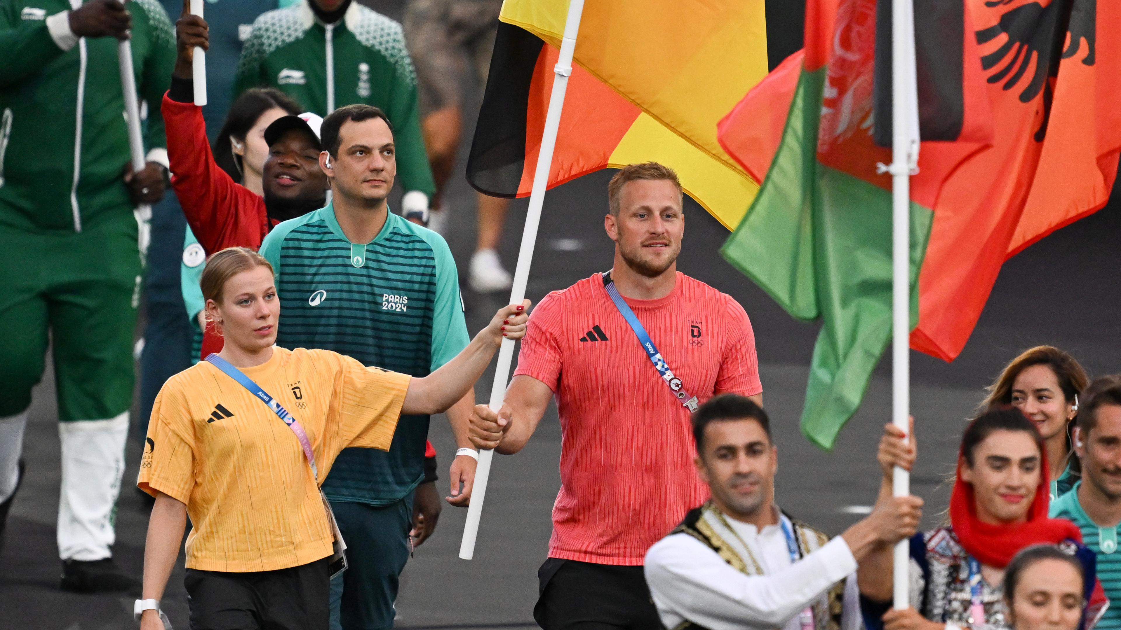 Triathletin Laura Lindemann und der Renn-Kanute Max Rendschmidt tragen bei der Schlussfeier die deutsche Fahne ins Stadion.