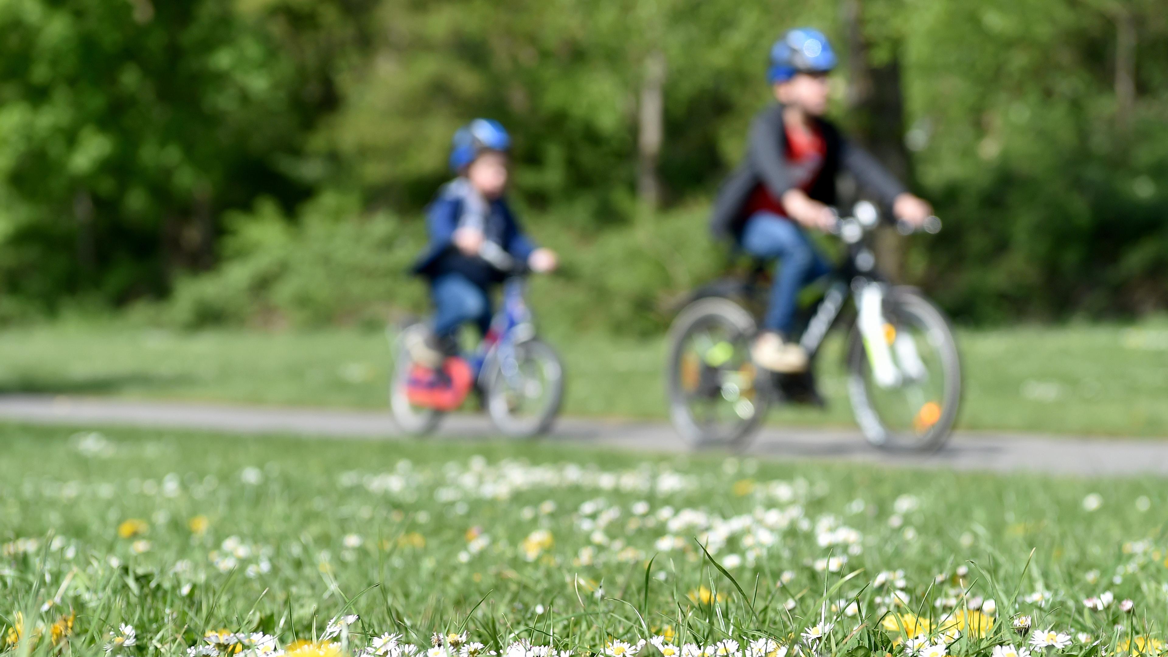 Zwei Kinder fahren Fahrrad im Grünen.