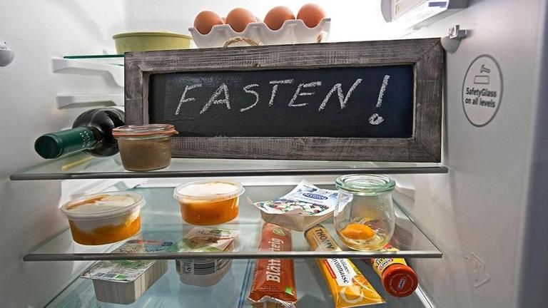 Eine Tafel mit der Aufschrift Fasten steht in einem Kühlschrank mit Lebensmitteln. Mit dem Aschermittwoch am beginnt die rund 40-tägige Fasten- oder Passionszeit vor Ostern.