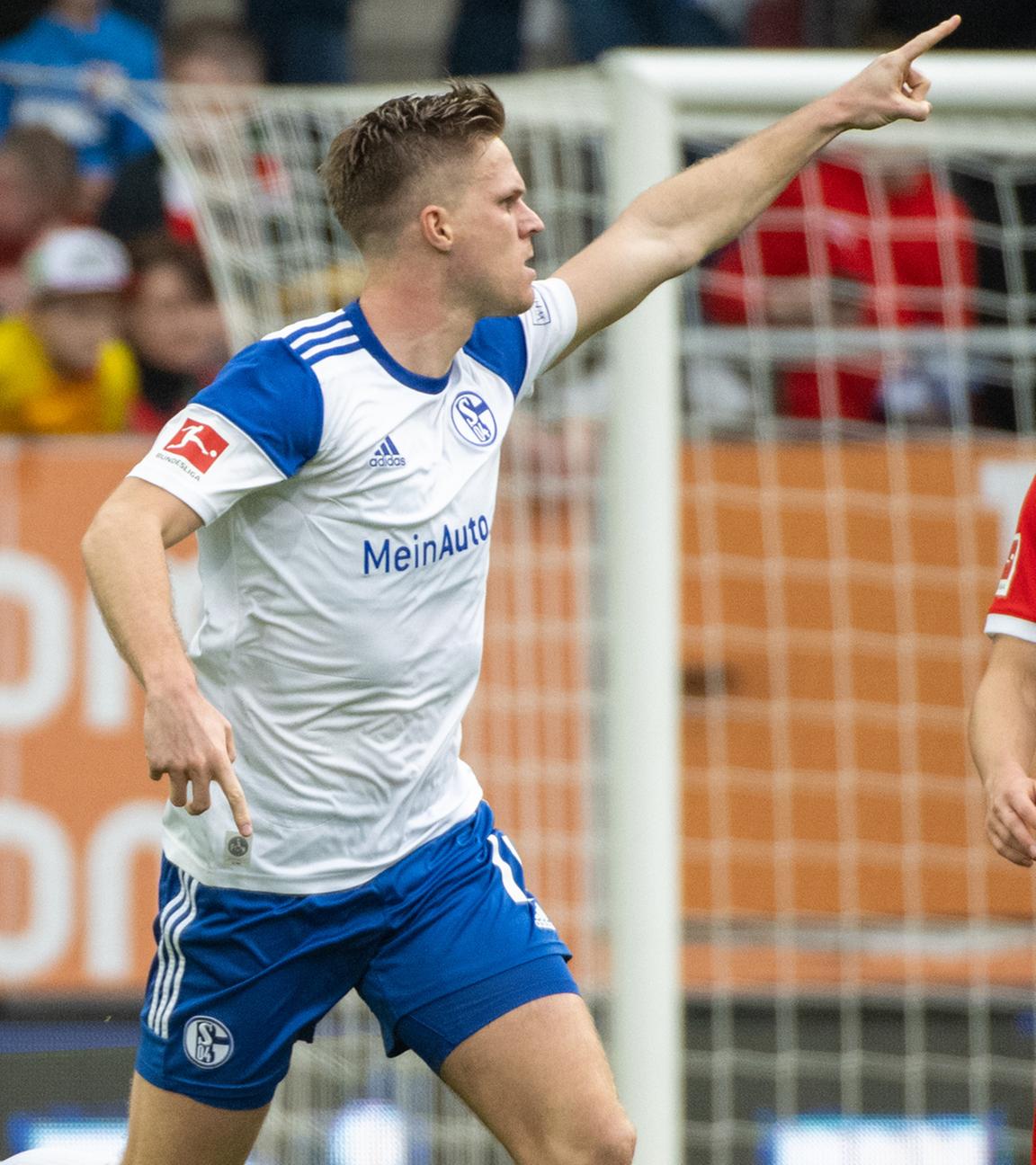 Augsburgs Robert Gumny (r) steht neben Schalkes jubelndem Marius Bütler nach seinem Tor zum 1:1.