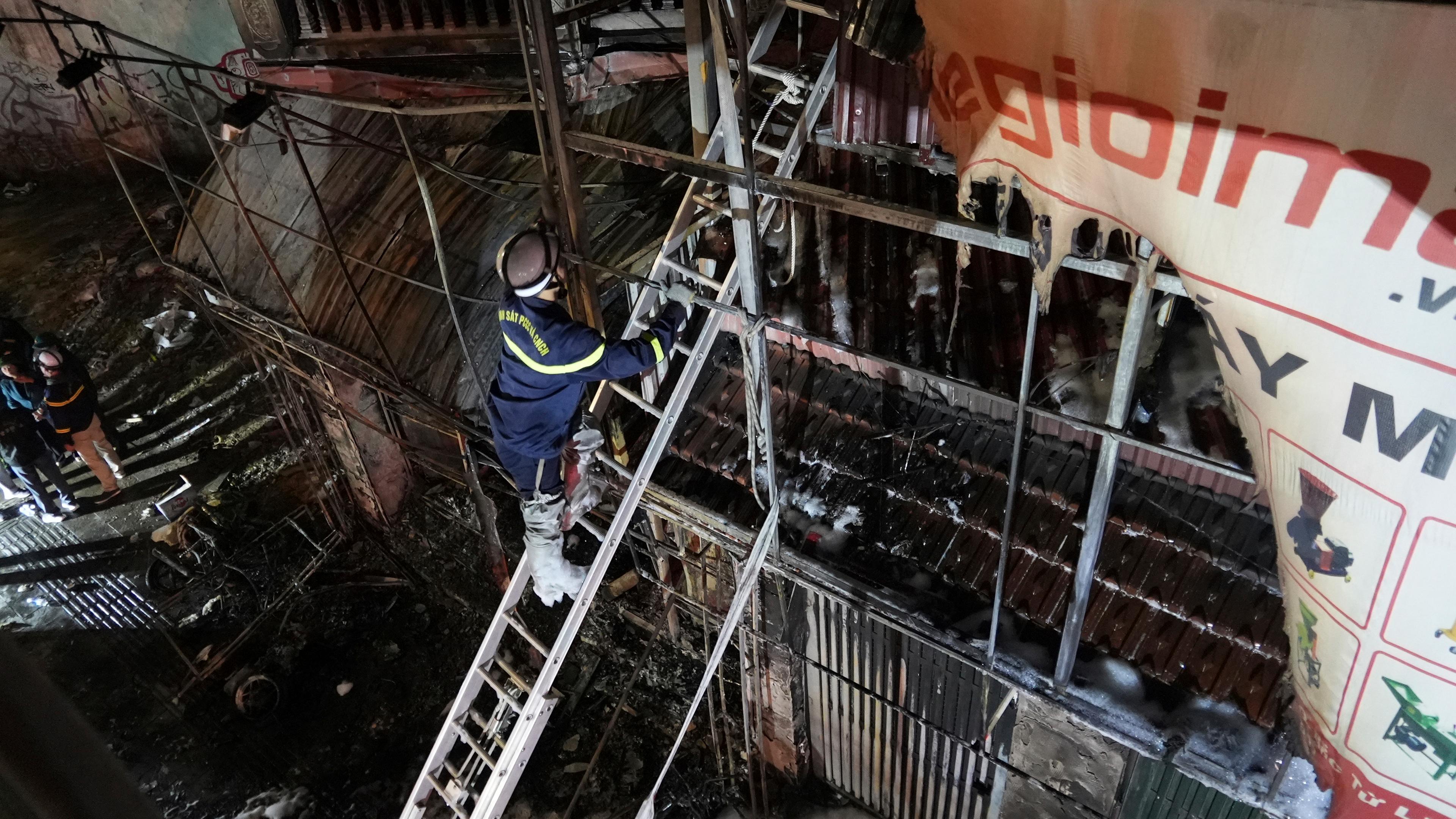 Vietnam, Hanoi: Feuerwehrleute inspizieren ein durch ein Feuer zerstörtes Gebäude.