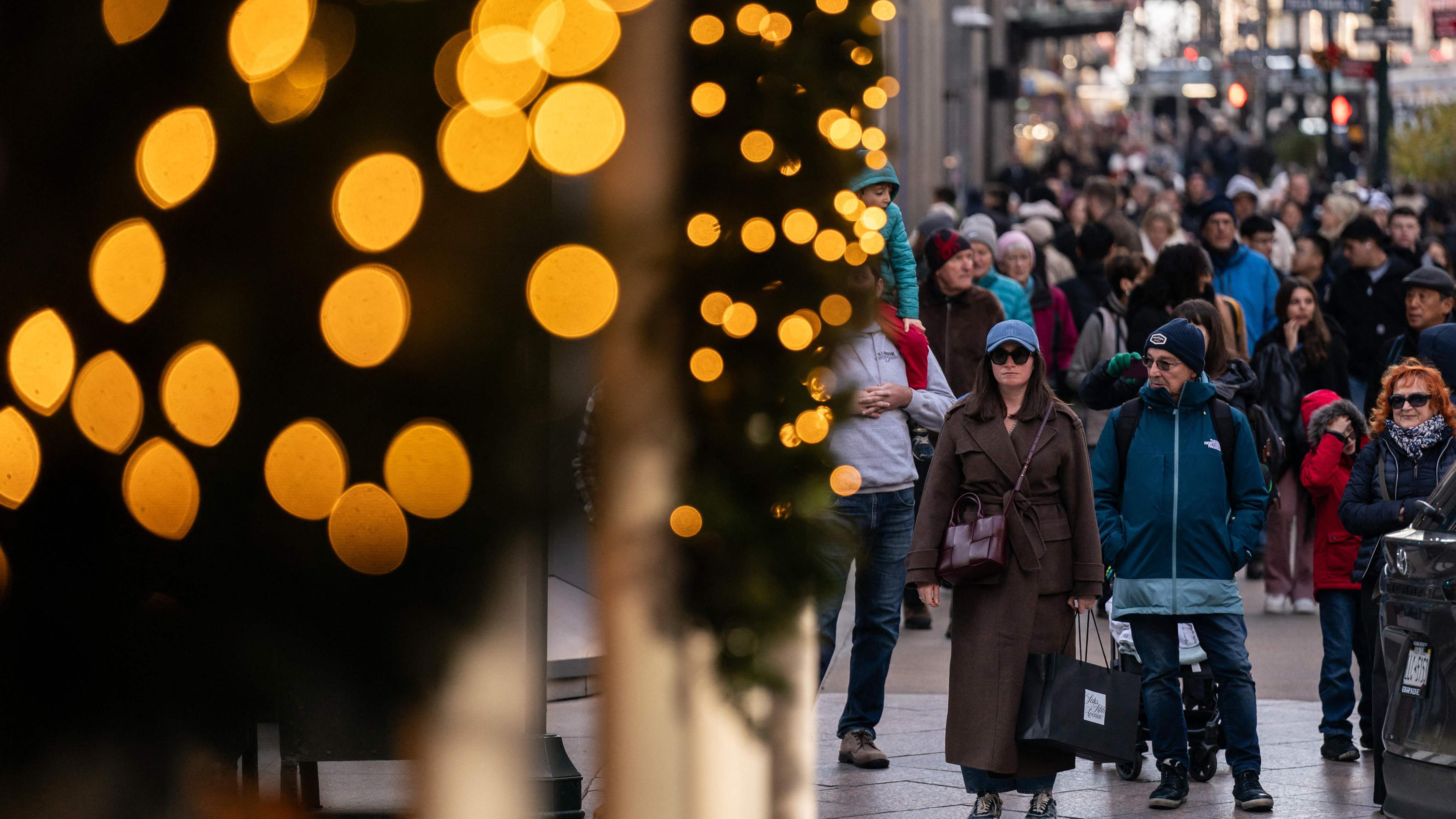 Leute laufen auf der Fifth Avenue in New York und tragen Einkaufstaschen.