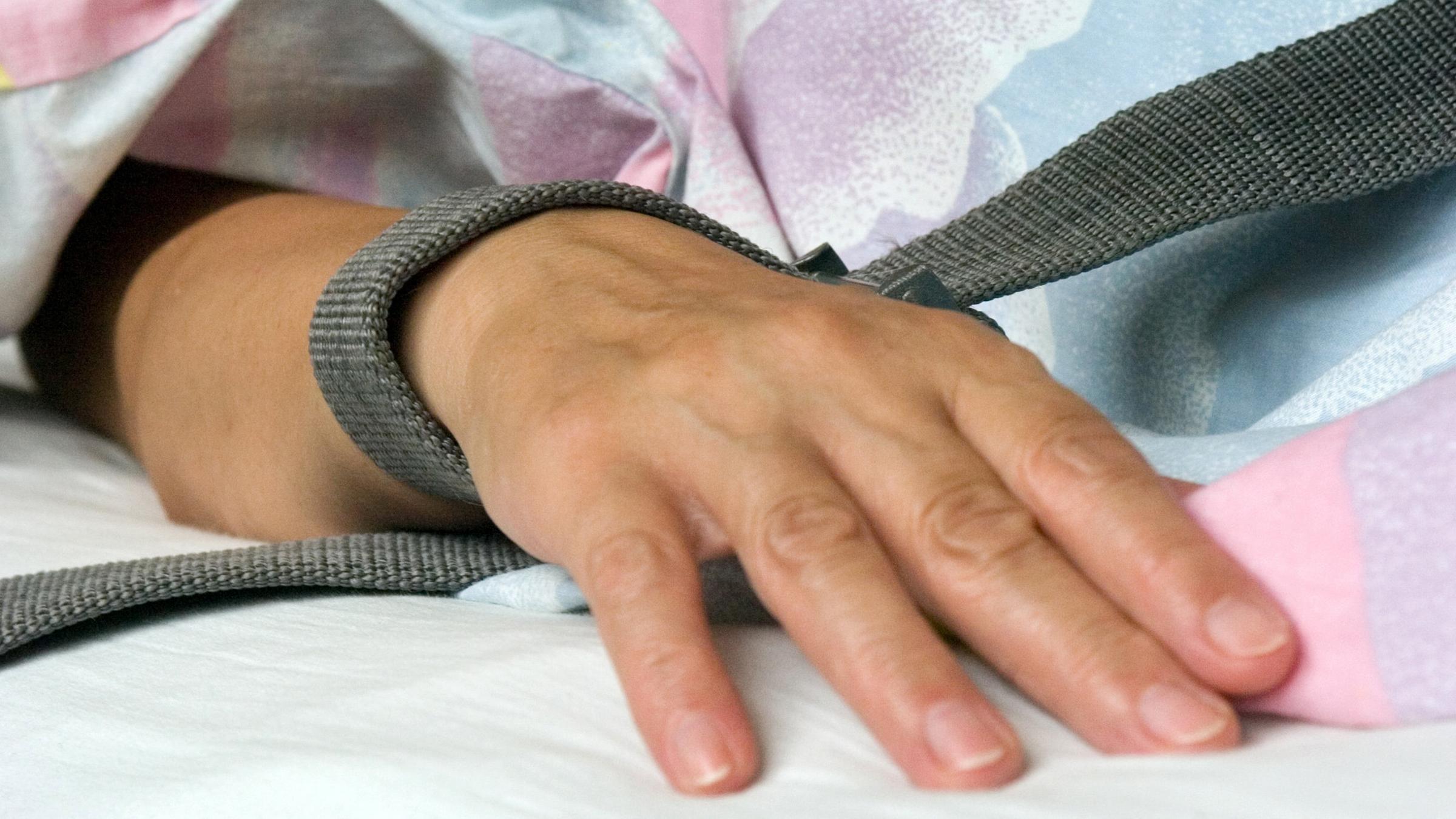 Eine mit einem Textilband festgebundene Hand eines Patienten, Archivbild