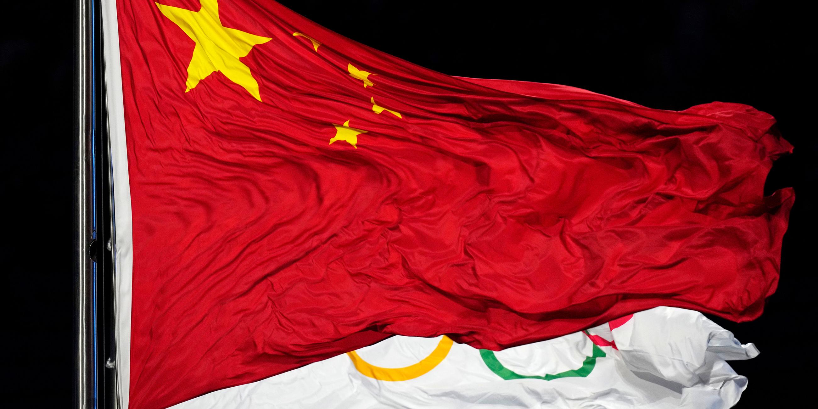 Chinas Flagge vor der Olympischen Flagge