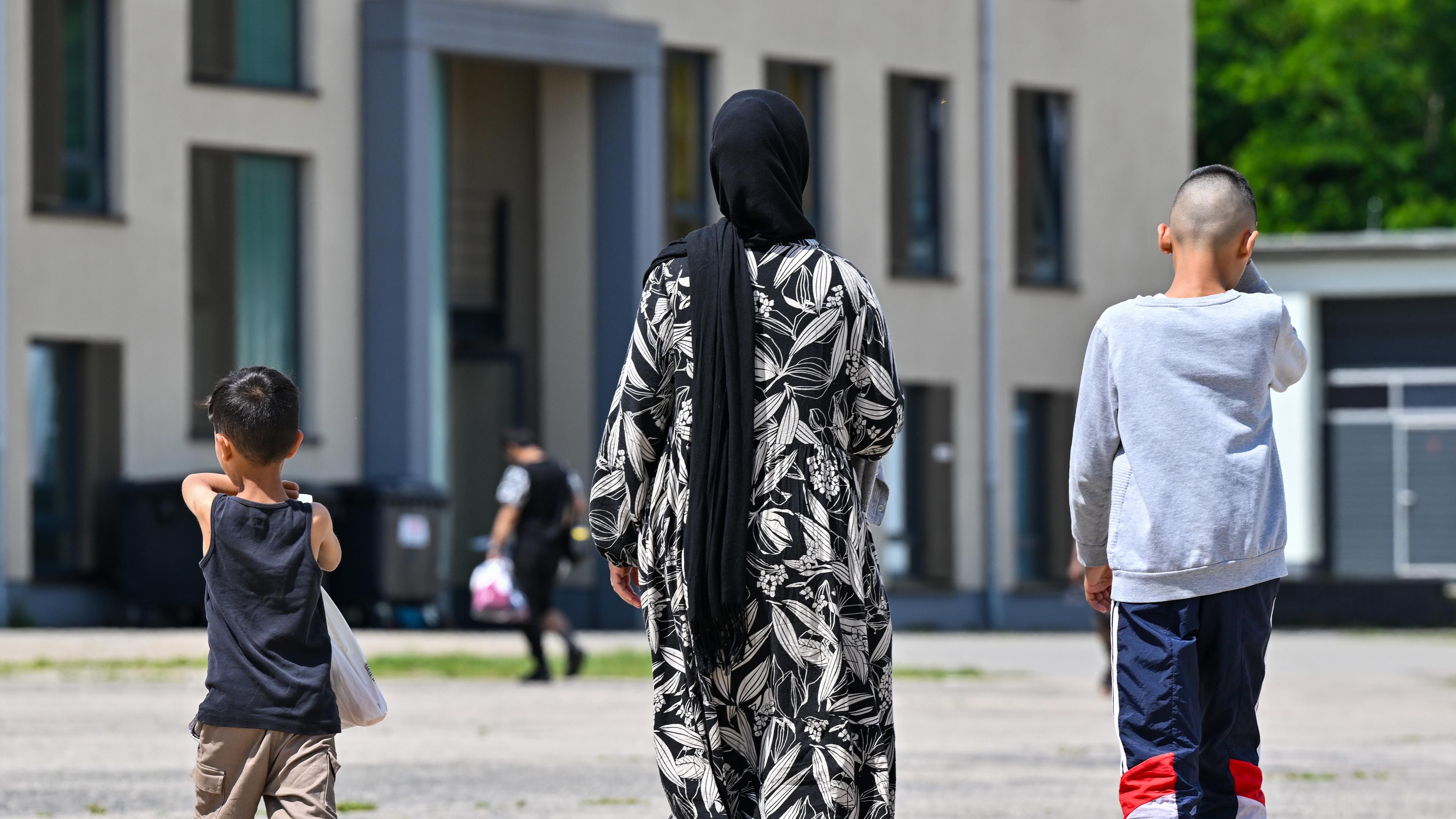 Eine Migrantin und ihre zwei Kinder gehen über das Gelände der Zentralen Erstaufnahmeeinrichtung für Asylbewerber (ZABH) des Landes Brandenburg.