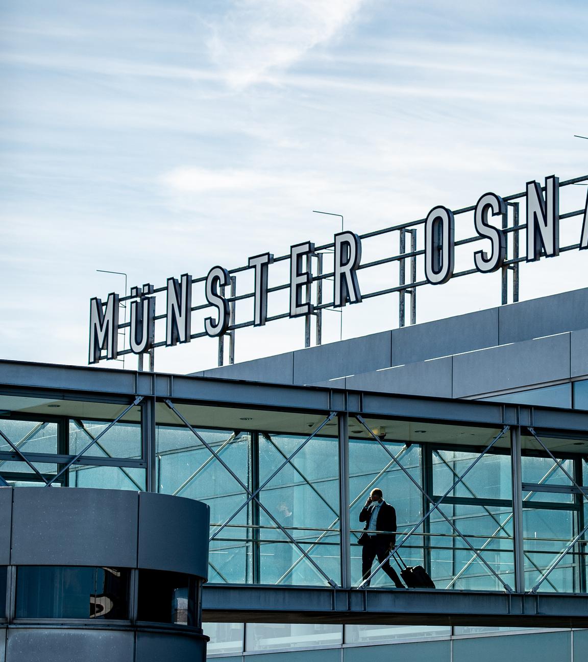 Zwei Passagiere gehen über die Gangway am Flughafen Münster-Osnabrück zu ihrem Flieger.