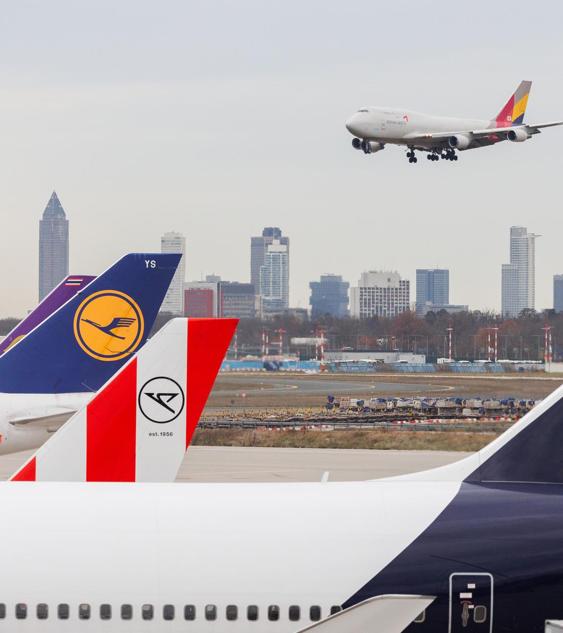 Am Frankfurter Flughafen stehen Flugzeuge, während ein Flugzeug zur Landung ansetzt.