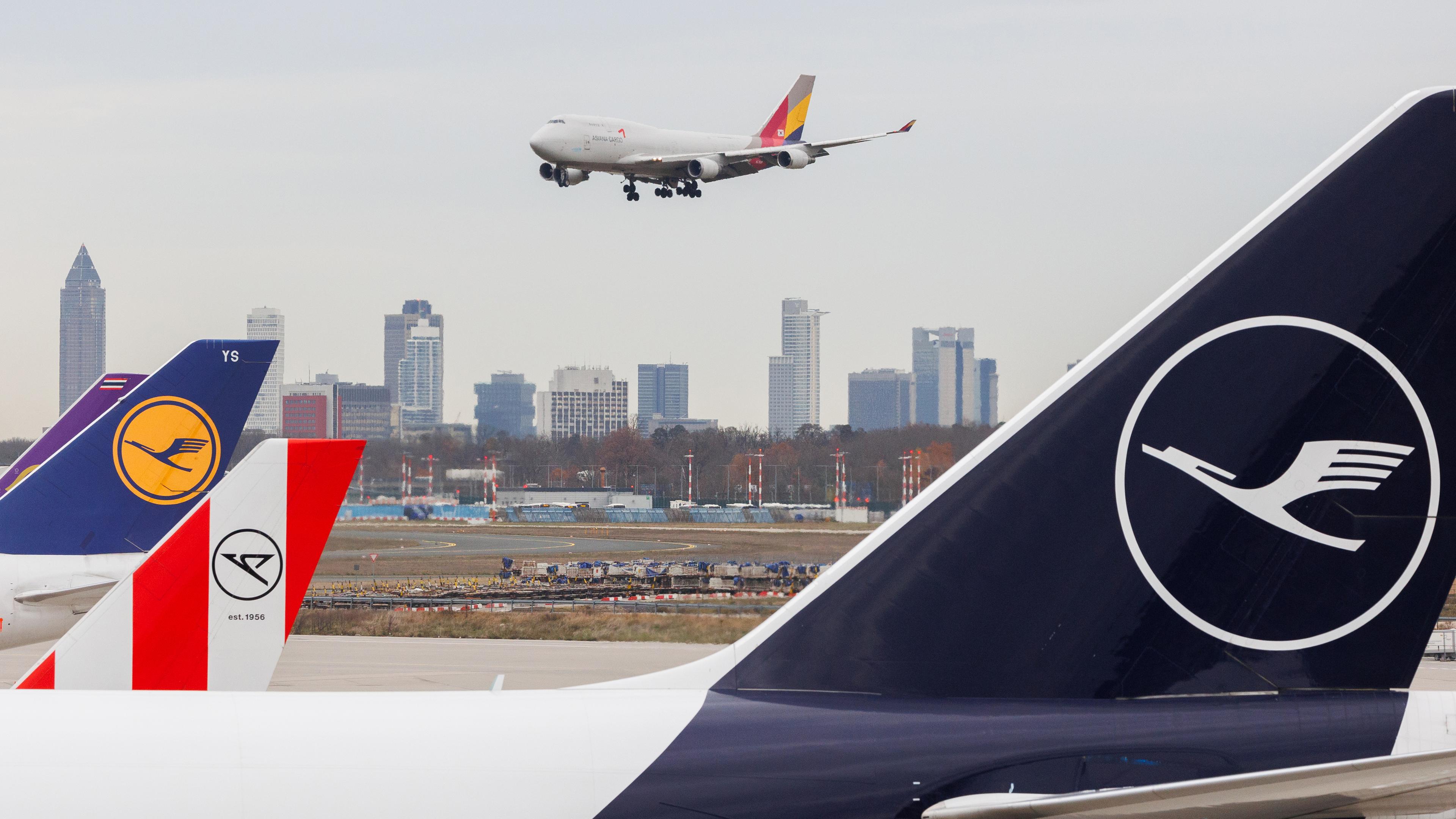 Am Frankfurter Flughafen stehen Flugzeuge, während ein Flugzeug zur Landung ansetzt.