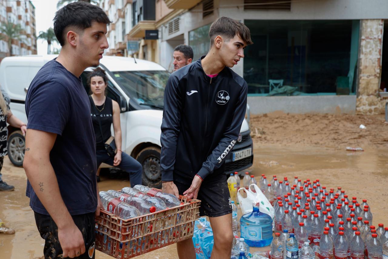 Menschen transportieren nach der Flut in Spanien Wasser.