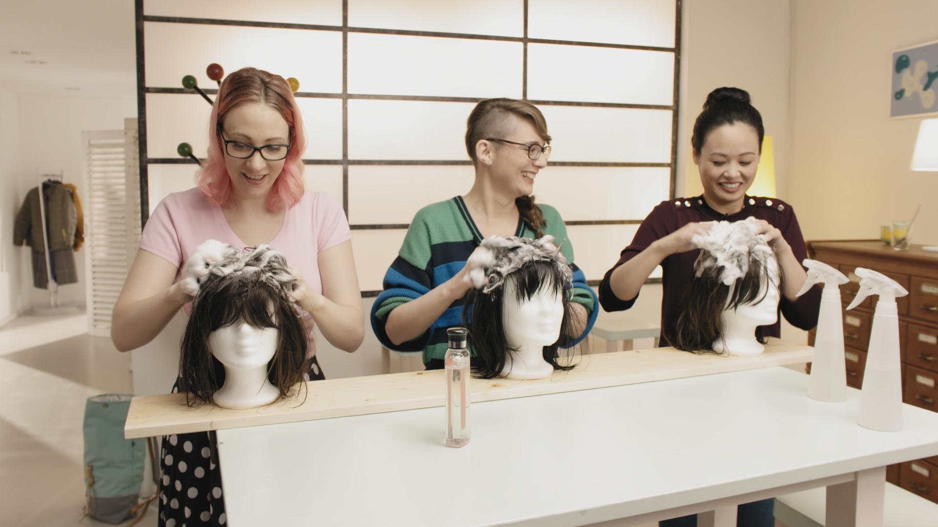 Johanna (li.), Patrizia (mi.) und Linh (re.) shamponieren die Haare der vor sich stehenden Puppenköpfe.