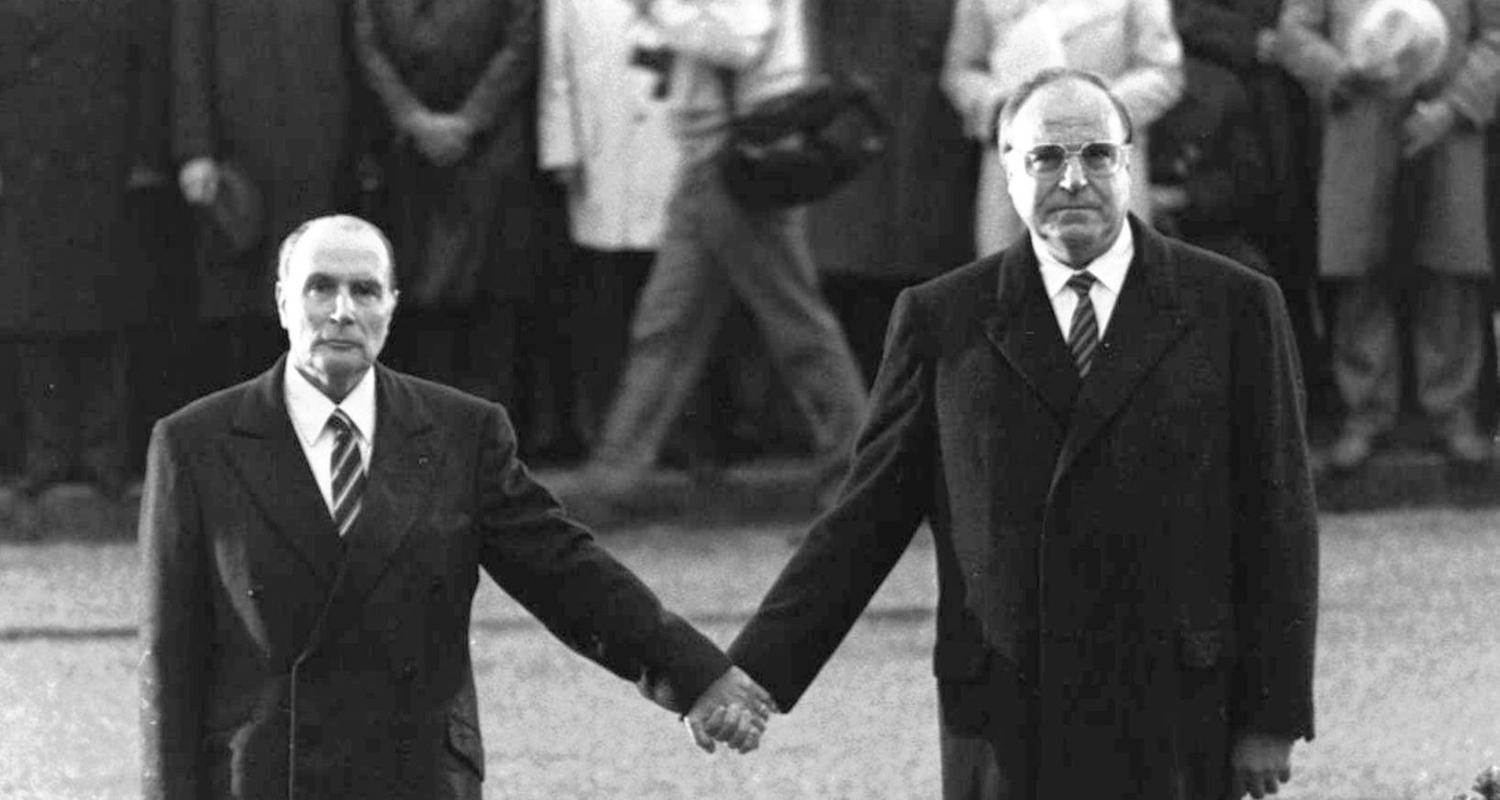 Francois Mitterrand und Helmut Kohl, wie sie während einer deutsch-französischen versöhnungszeremonie vor dem Friedhof von Doaumont händchenhaltend ihre jeweiligen Nationalhymnen hören.
