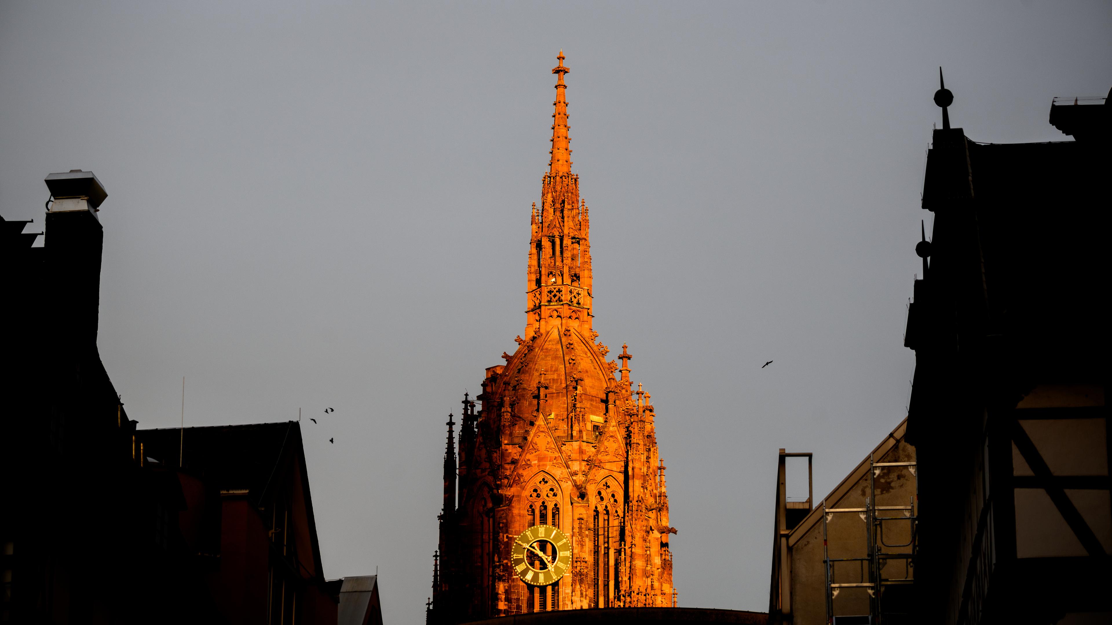 Der Turm des Doms St. Bartholomäus wird von der Abendsonne angestrahlt.