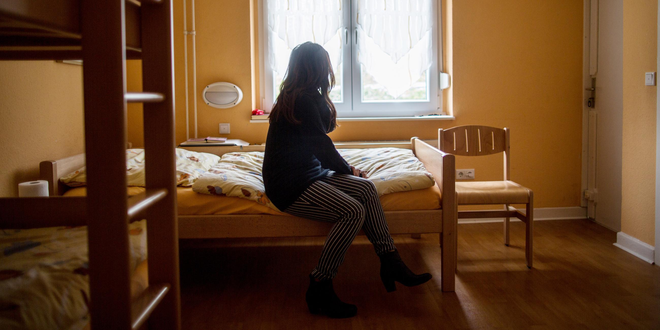 Frau sitzt auf einem Bett in einem Frauenhaus in Herne