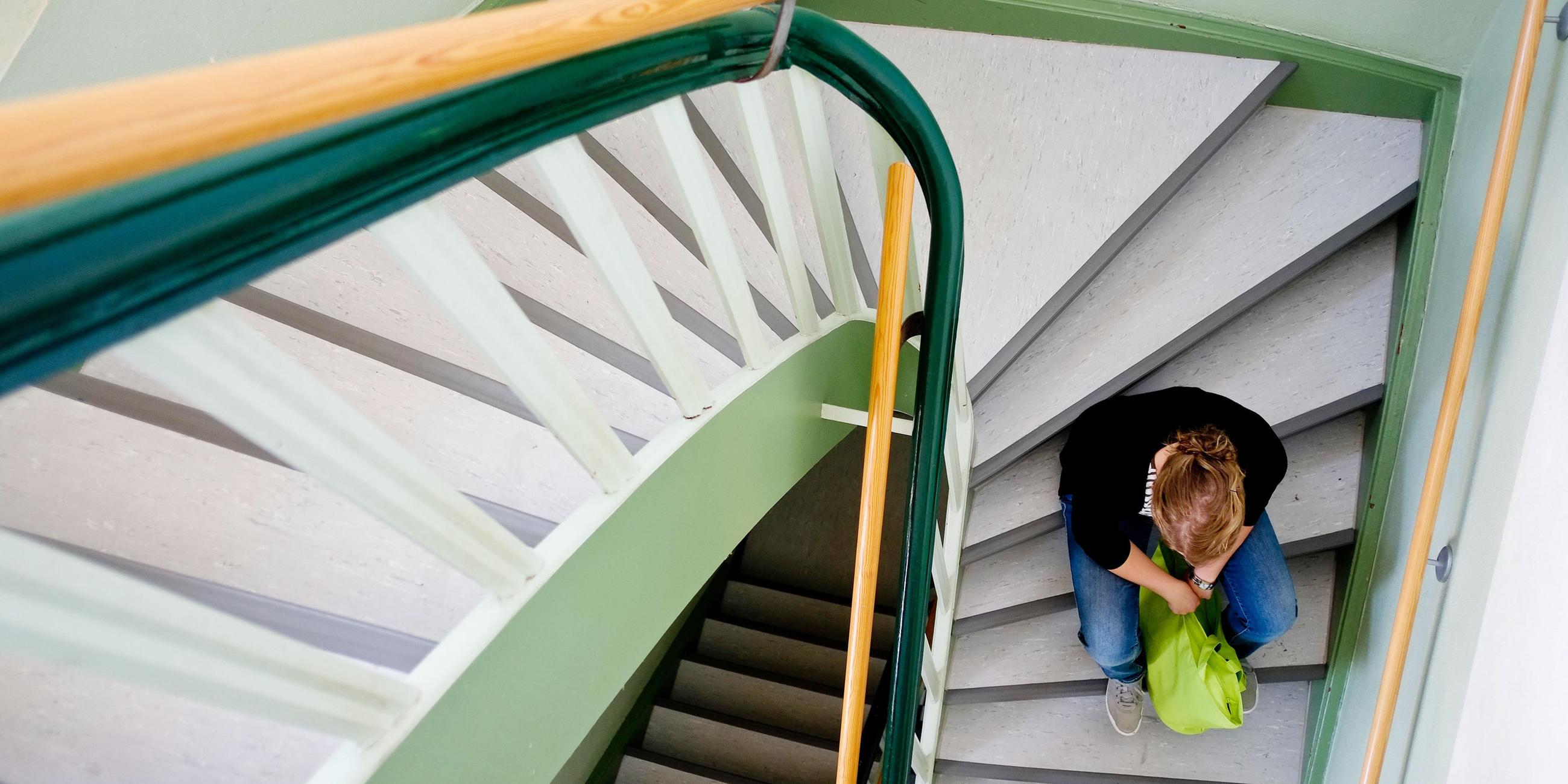 Eine junge Frau sitzt am 28.08.2013 auf einer Treppe. Frauenhäuser in Sachsen sehen sich dennoch am Limit.