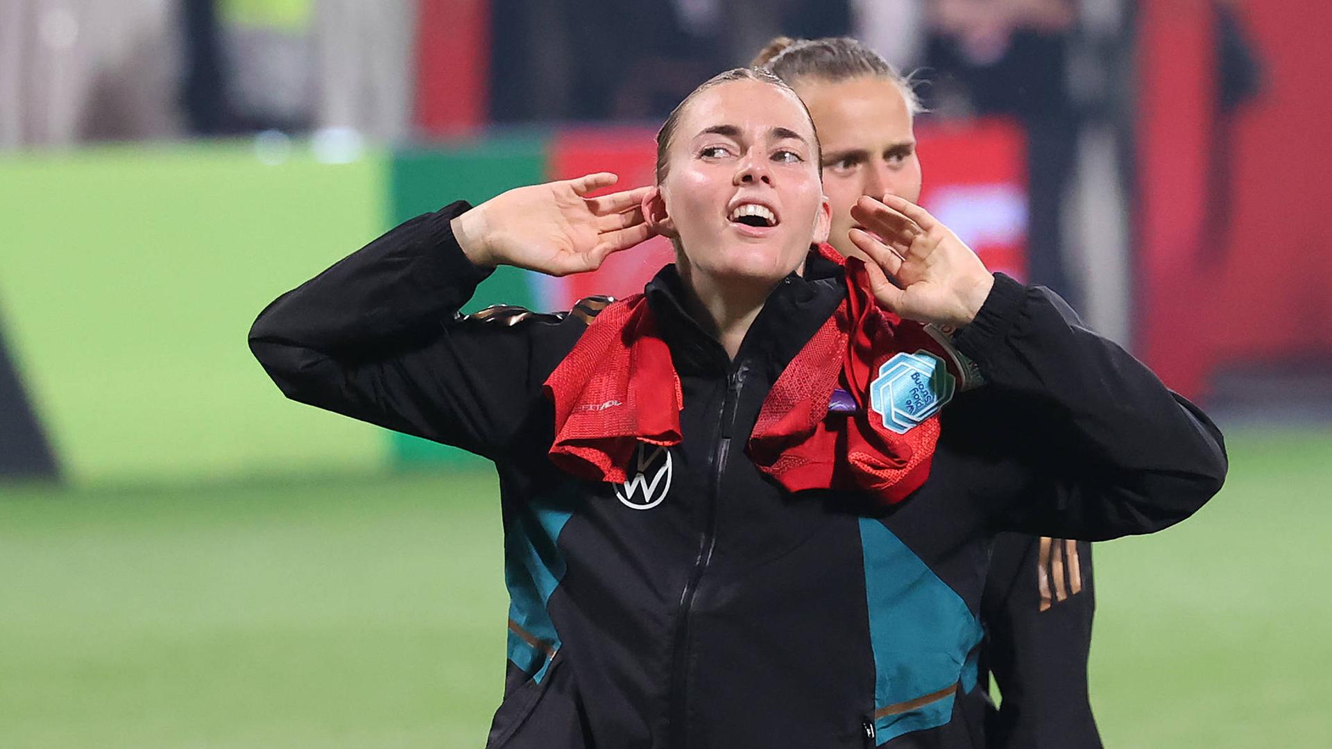 Laura Freigang fordert nach dem 4:1-Sieg der DFB-Frauen in Rostock gegen Polen die Fans zu singen auf und hält sich beide Hände an die Ohrmuscheln.