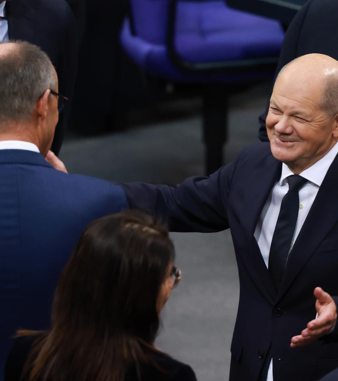 Bundeskanzler Olaf Scholz (r.) spricht mit dem CDU-Fraktionsvorsitzenden Friedrich Merz (l.) vor seiner Rede im Deutschen Bundestag in Berlin