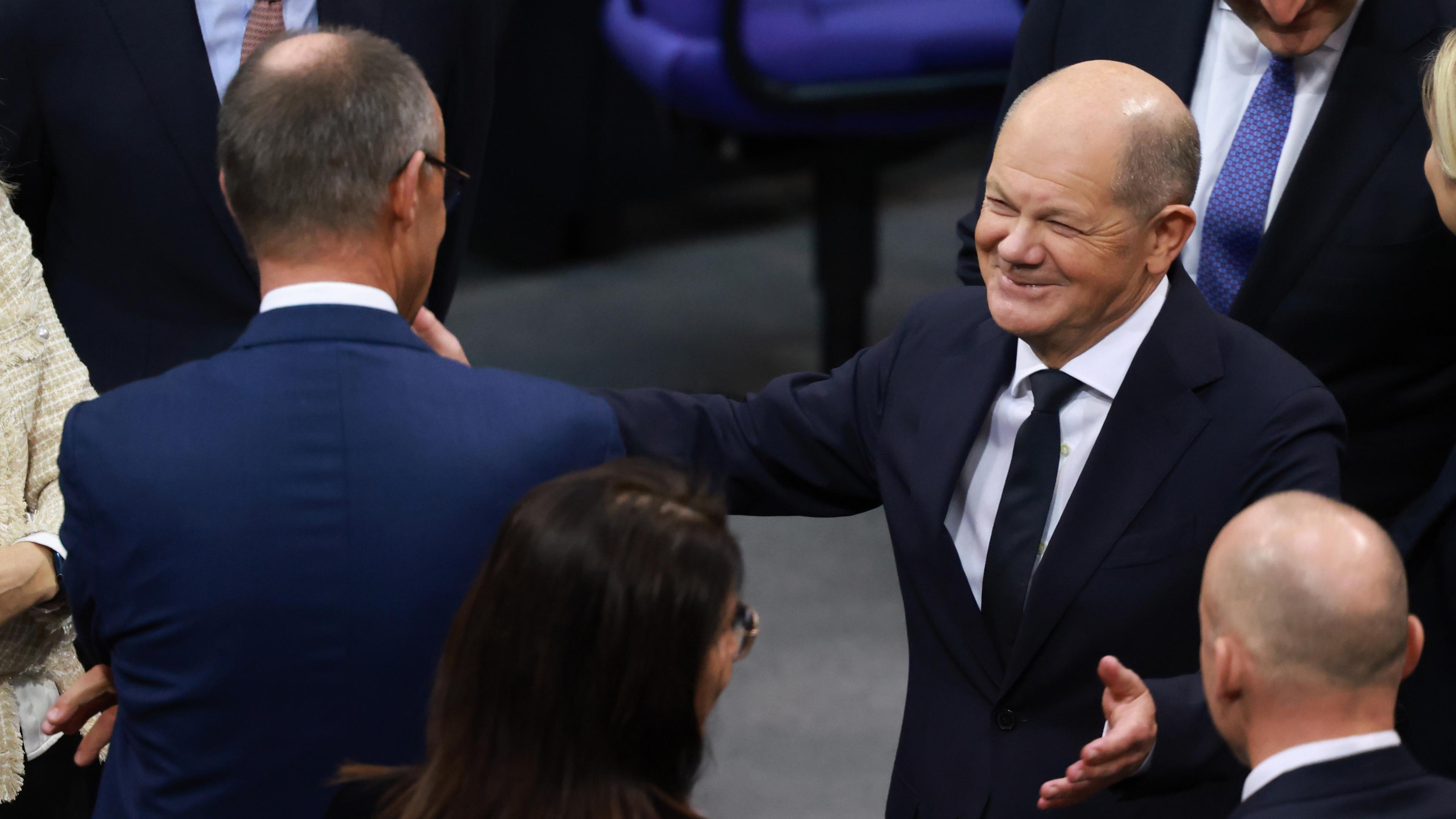 Bundeskanzler Olaf Scholz (r.) spricht mit dem CDU-Fraktionsvorsitzenden Friedrich Merz (l.) vor seiner Rede im Deutschen Bundestag in Berlin