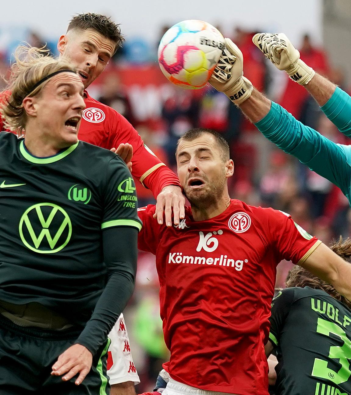 Wolfsburgs Sebastiaan Bornauw (l-r), der Mainzer Alexander Hack und Wolfsburgs Torwart Koen Casteels kämpfen um den Ball am 05.11.2022 in Mainz.