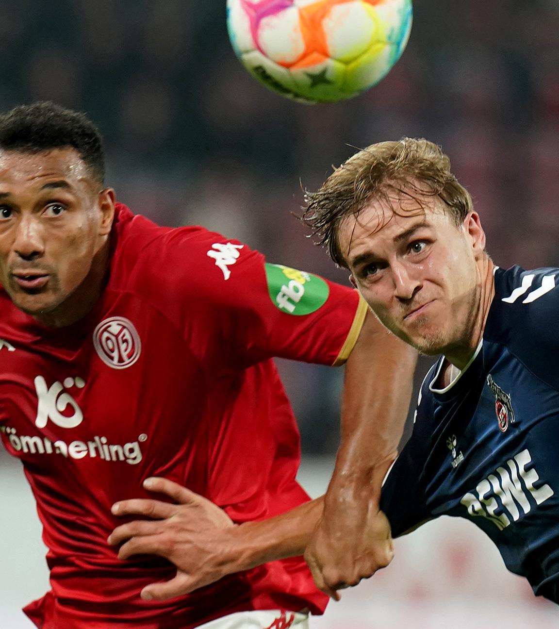 Der Kölner Timo Hubers (r) und der Mainzer Karim Onisiwo kämpfen um den Ball am 21.10.2022 in Mainz.