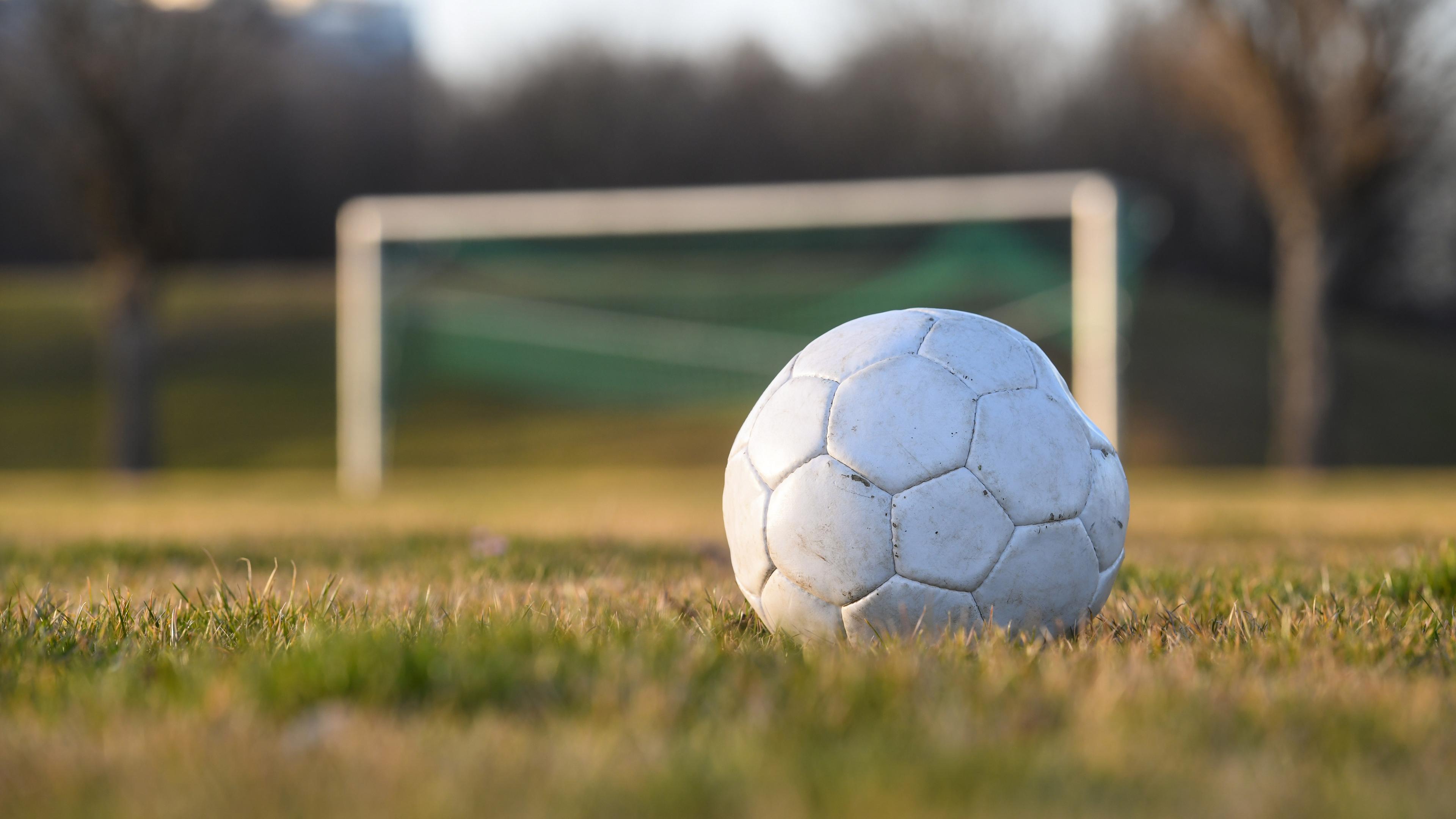 Fußball liegt auf einem Fußballplatz im Hintergrund sieht man ein leeres Fußballtor.