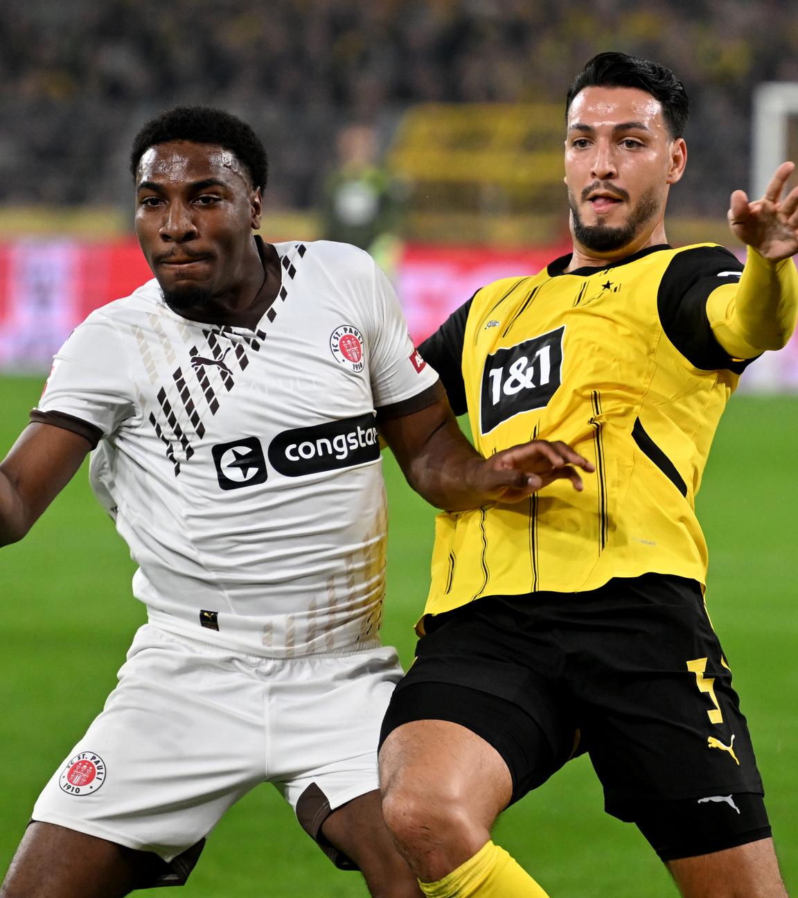 Fußball: St. Paulis Oladapo Afolayan (l.) und Dortmunds Ramy Bensebaini. 