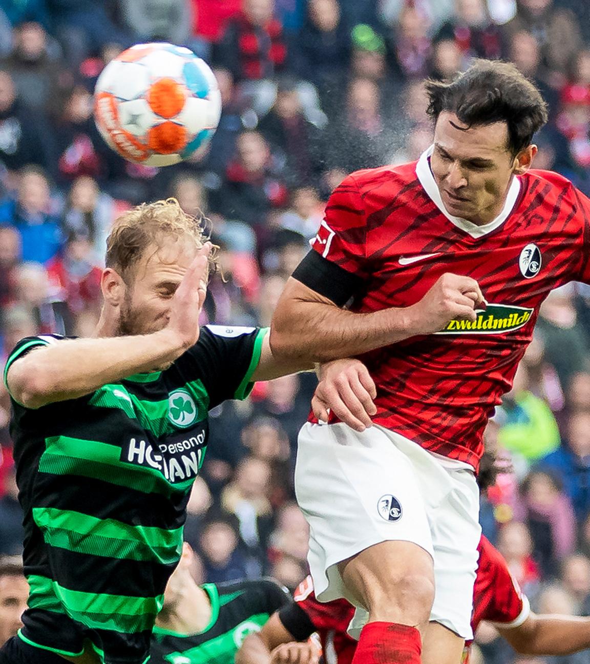 Freiburgs Nicolas Höfler (r) macht das Tor zum 2:0 gegen Fürths Sebastian Griesbeck (l) am 30.10.2021 im Europa-Park Stadion.