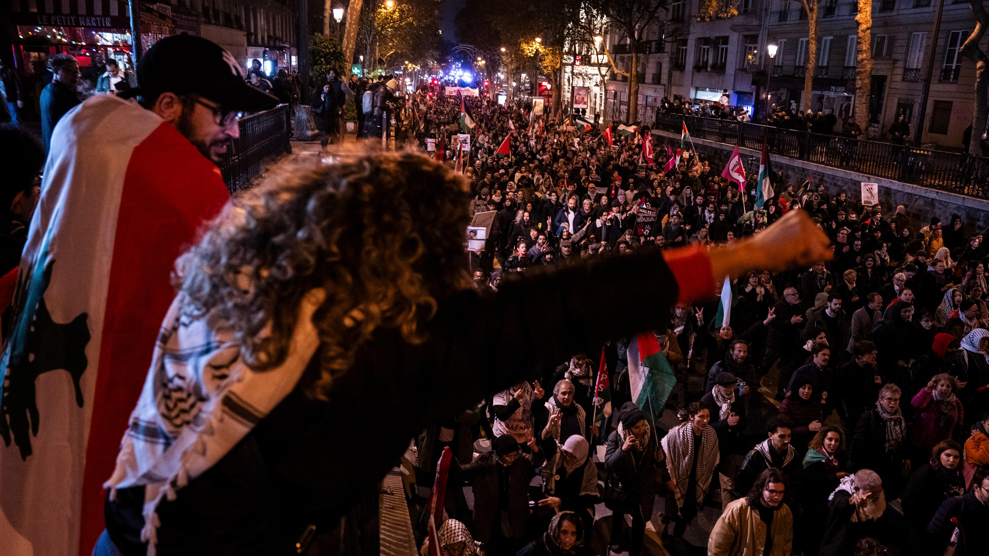 Eine Frau reckt die Faust in die Luft vor einer Menge von Demonstranten in Paris.