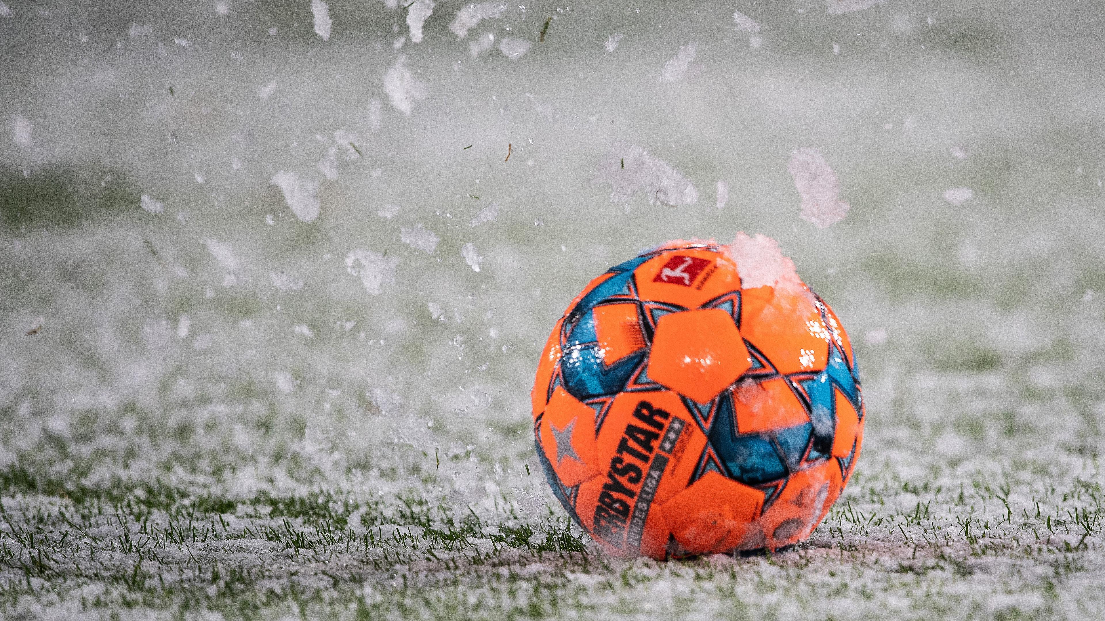 Archiv: Der Spielball rollt über den mit Schnee bedeckten Rasen