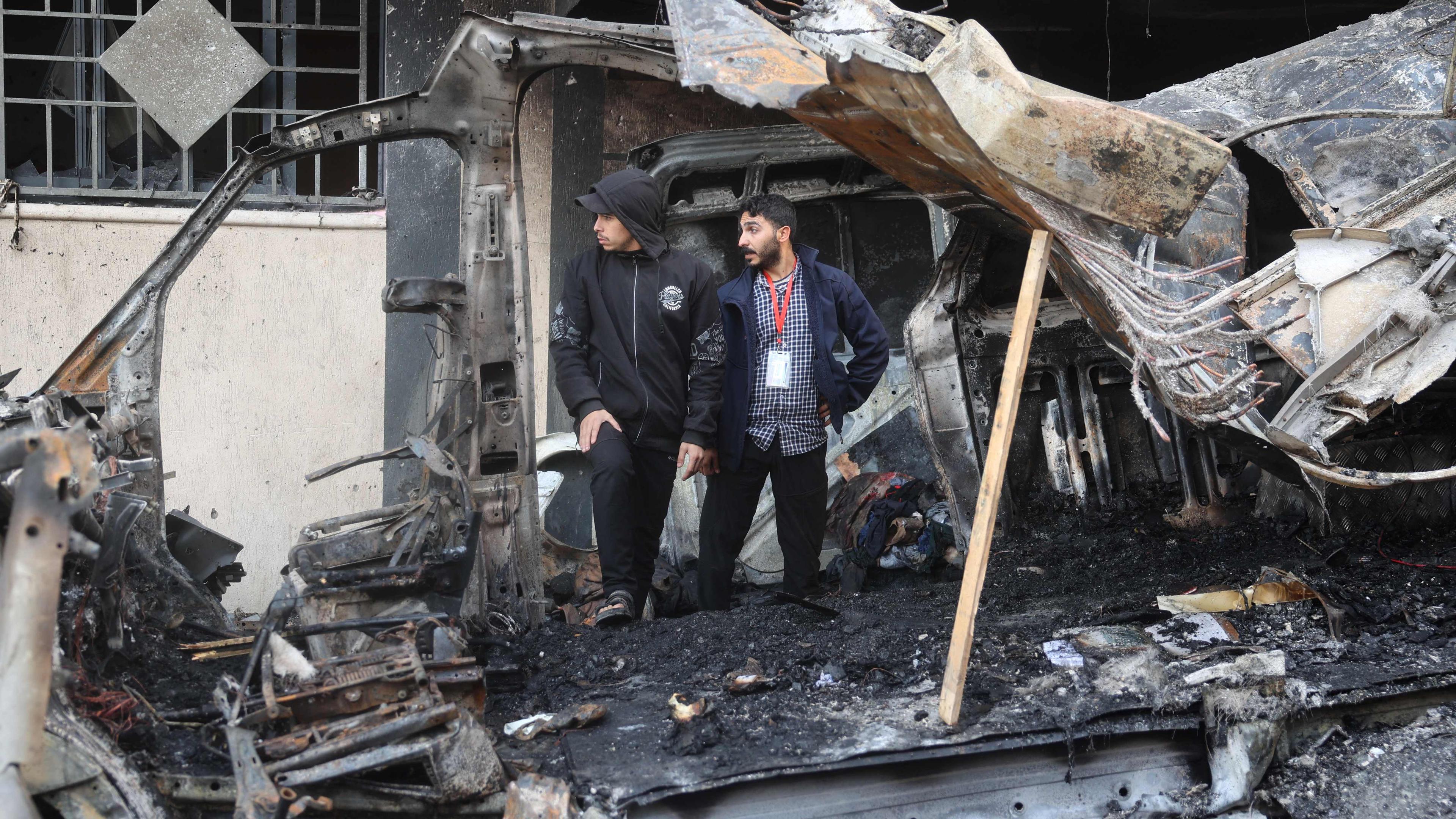 Zwei Männer stehen in einem zerstörten Laster im Gazastreifen