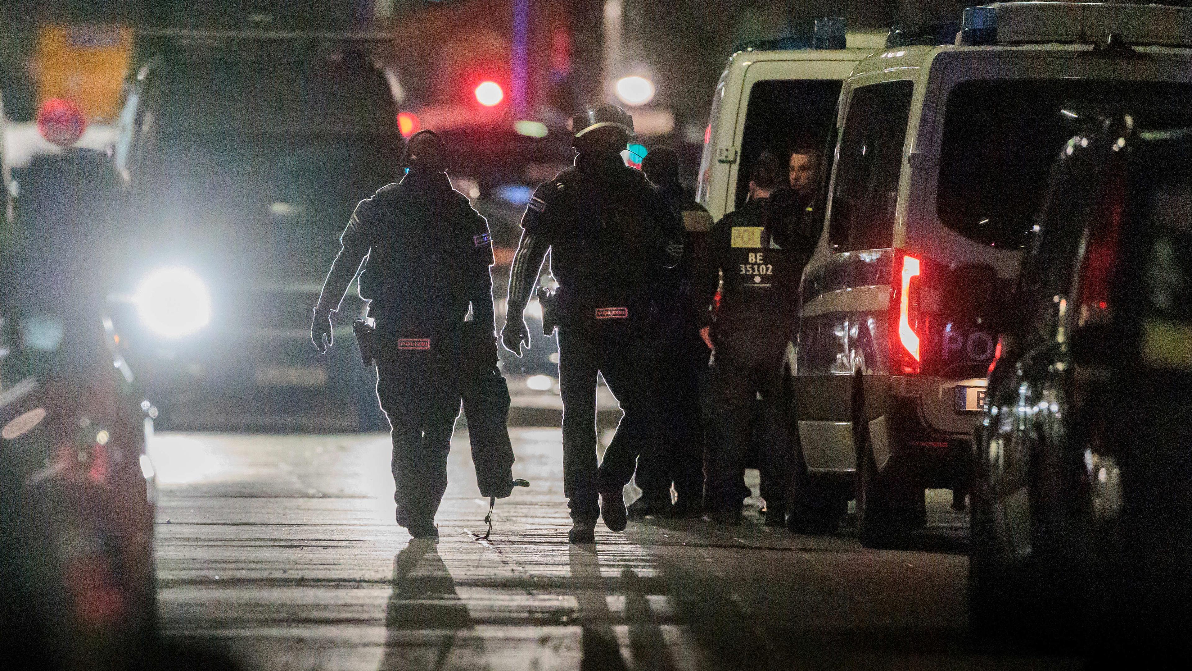 Polizisten gehen zu den Einsatzfahrzeugen nach der Beendigung einer Geiselnahme in einem Geschäft an der Keithstraße in Berlin-Schöneberg, aufgenommen am 25.04.2023