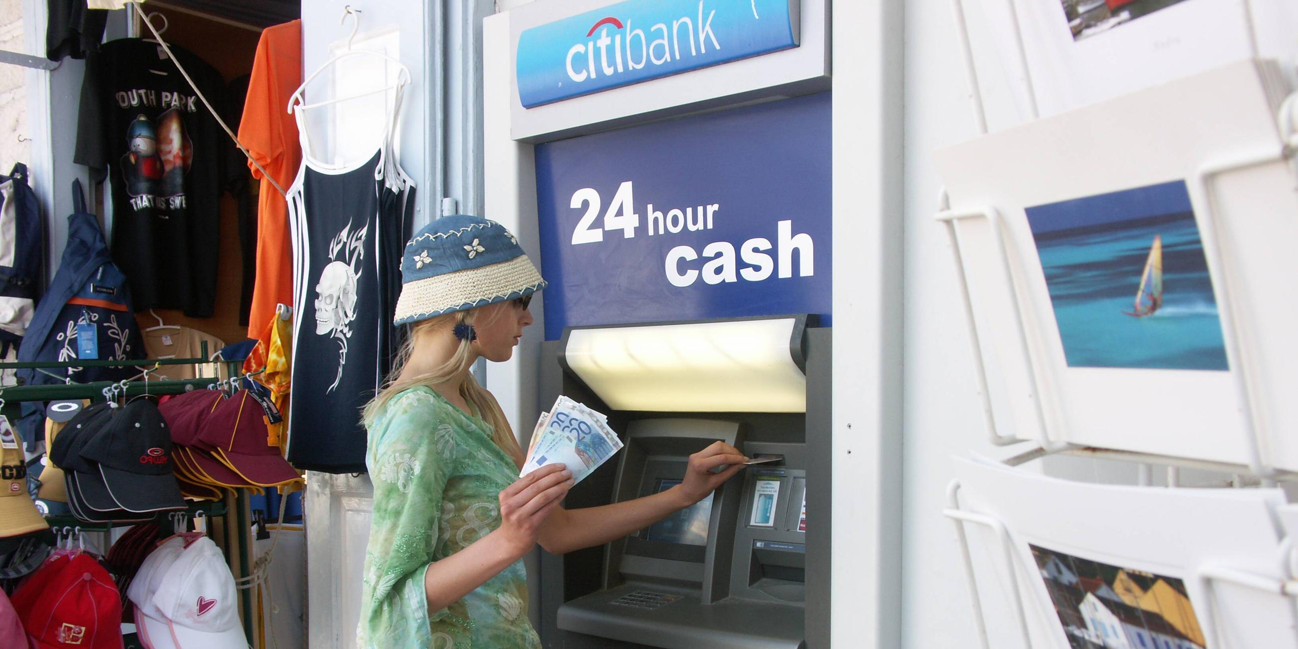 Frau hebt Geld an einem Automaten im Ausland ab.