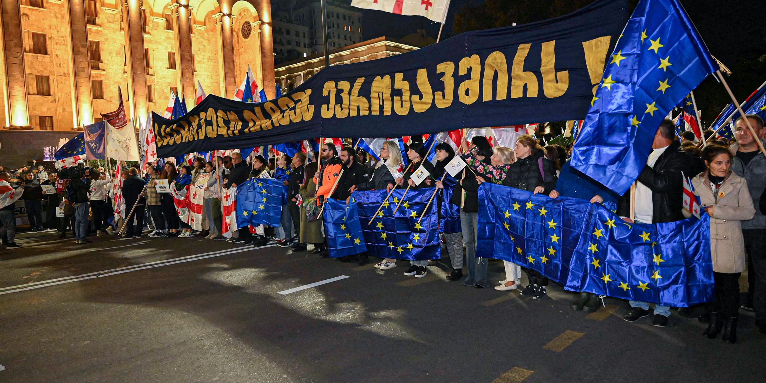 Menschen halten Fahnen von Georgien und der EU bei Protestmarsch