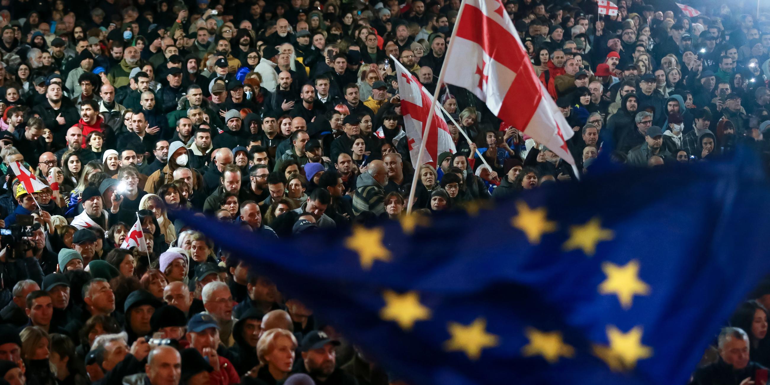 Demonstranten schwenken EU- und georgische Nationalflaggen, während sie an einer Kundgebung gegen angebliche Verstöße bei den jüngsten Parlamentswahlen teilnehmen.