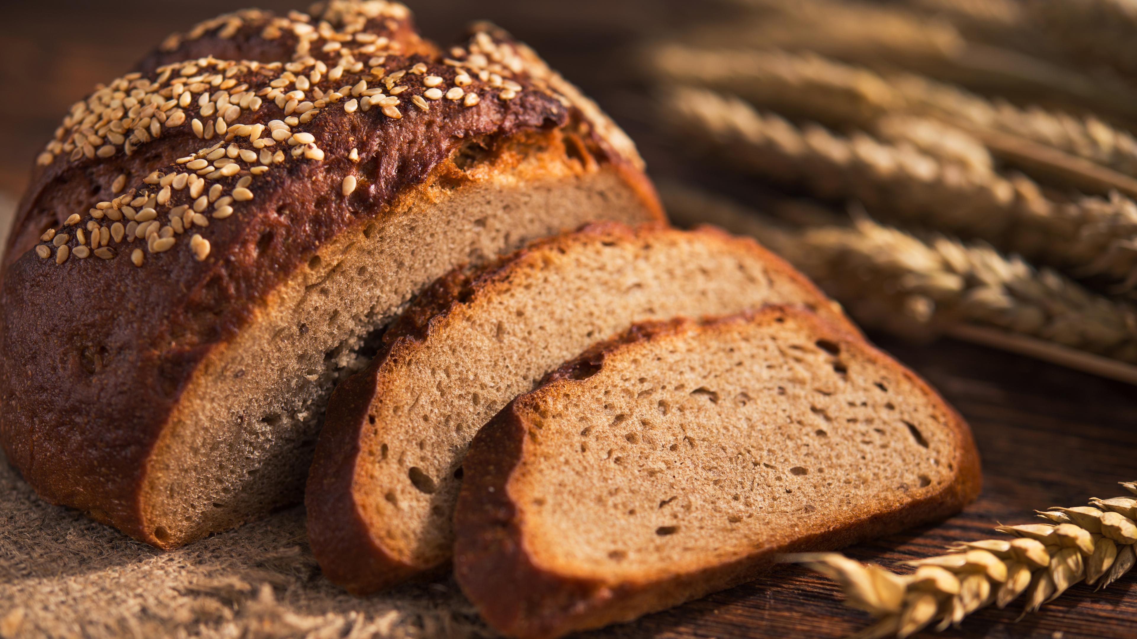 Ein halbes Laib Brot liegt mit zwei Brotscheiben auf einem hölzernen Untergrund.