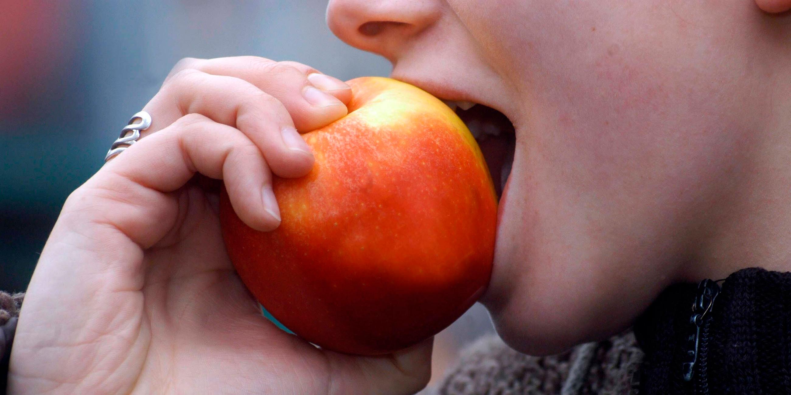 Eine Frau beißt in einen Apfel.