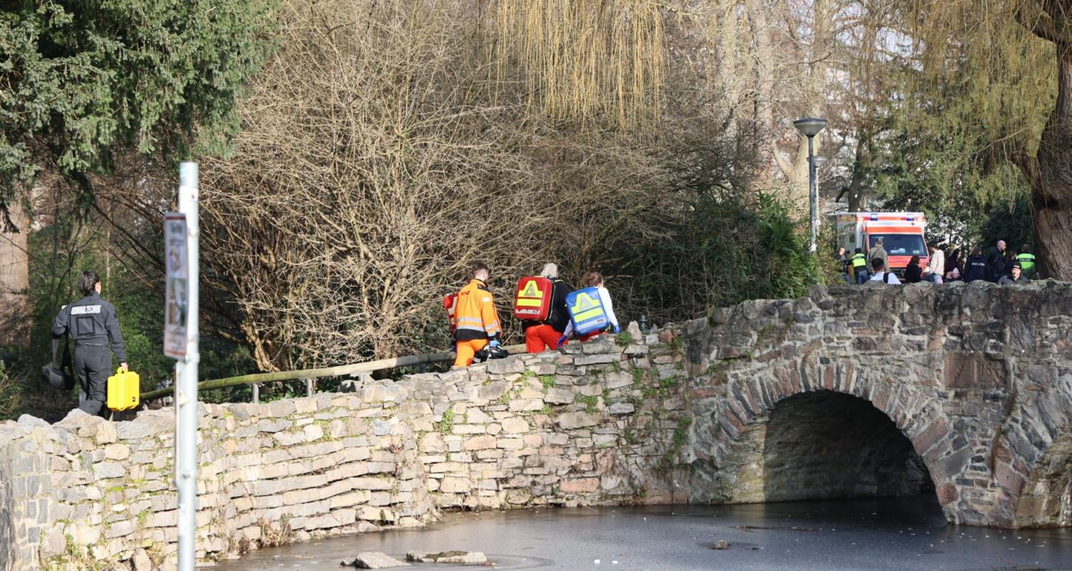 Bayern, Aschaffenburg: Rettungskräfte und Kriminaltechniker gehen in der Nähe eines Tatortes eine kleine Brücke hinauf.