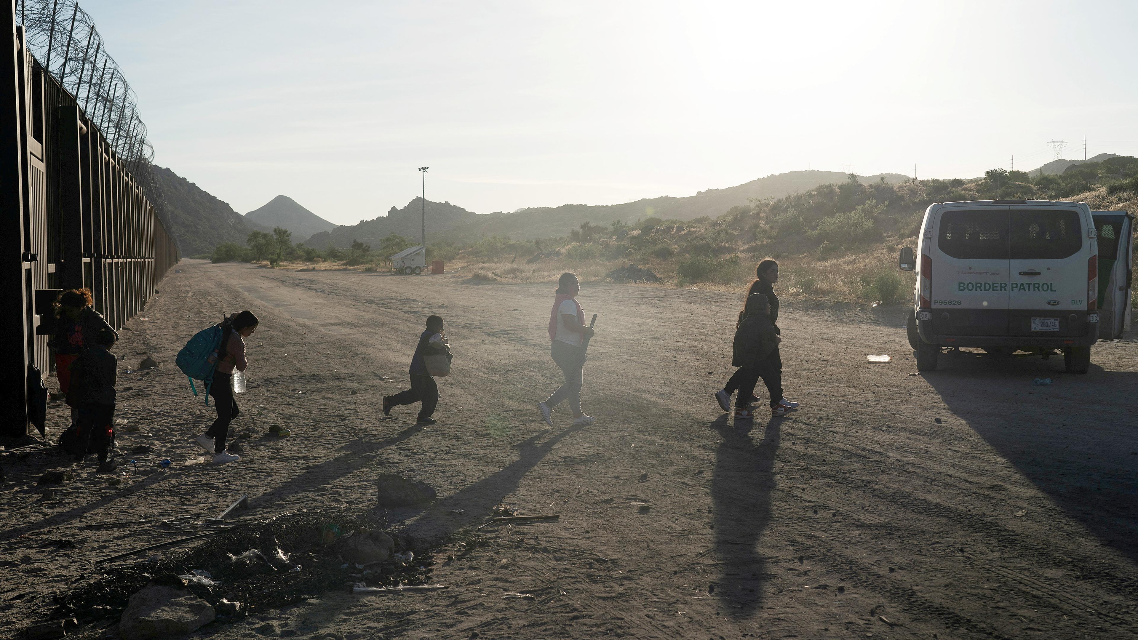 Asylsuchende Migranten aus Mexiko gehen zu einem Grenzpatrouillenwagen, um transportiert zu werden