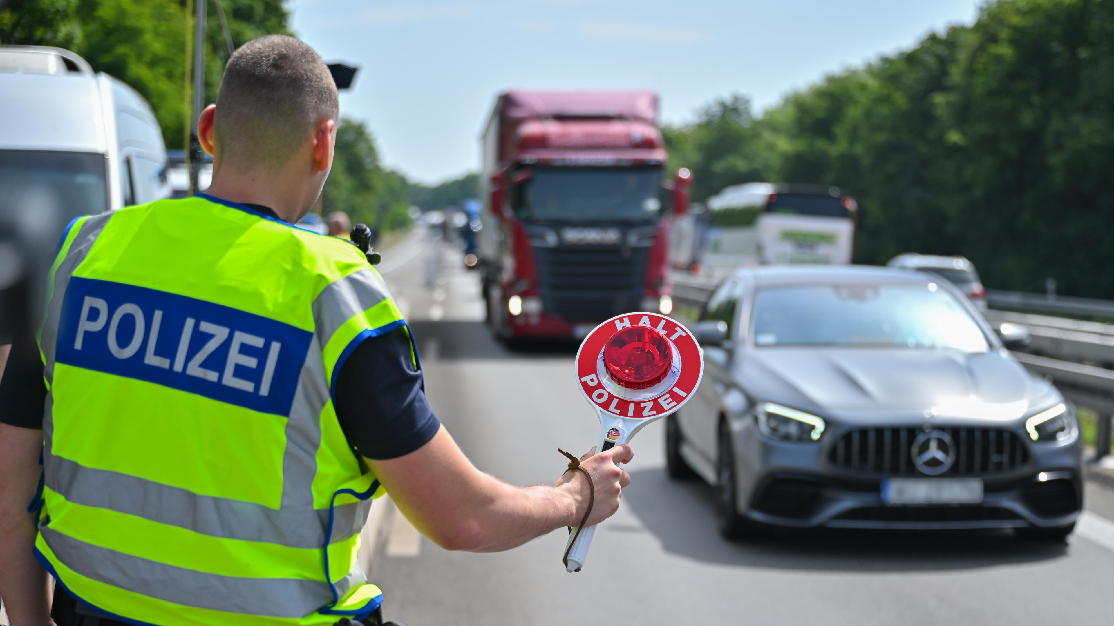 Ein Beamter der Bundespolizei steht auf der Autobahn A12 nahe dem deutsch-polnischen Grenzübergang und stoppt ein Auto mit polnischen Fußballfans, die unterwegs nach Berlin zum EM-Spiel Polen gegen Österreich sind.