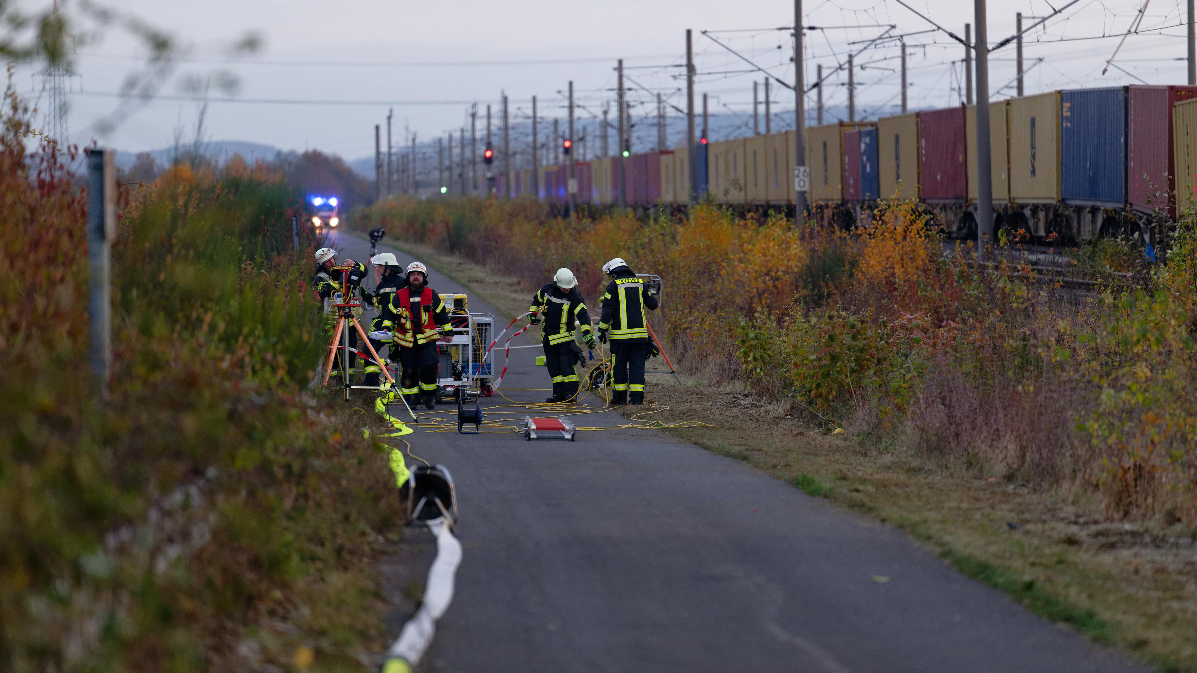 Feuerwehrleute sind neben dem entgleisten Güterzug und einem Bauzug auf der Bahnstrecke bei Kerpen im Einsatz.