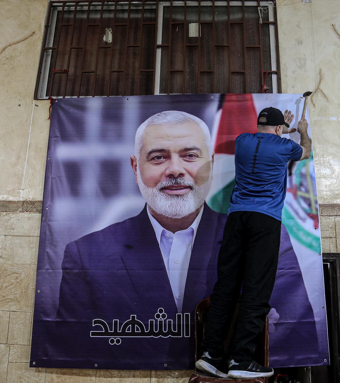 Libanon, Beirut: Ein Palästinenser hängt ein großes Bild von Ismail Hanija in einer Halle im palästinensischen Flüchtlingslager Burj al-Brajneh auf. 