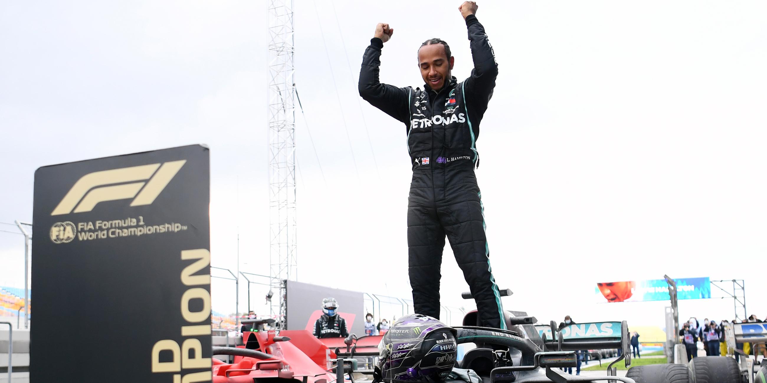 Lewis Hamilton jubelt auf seinem Auto stehend