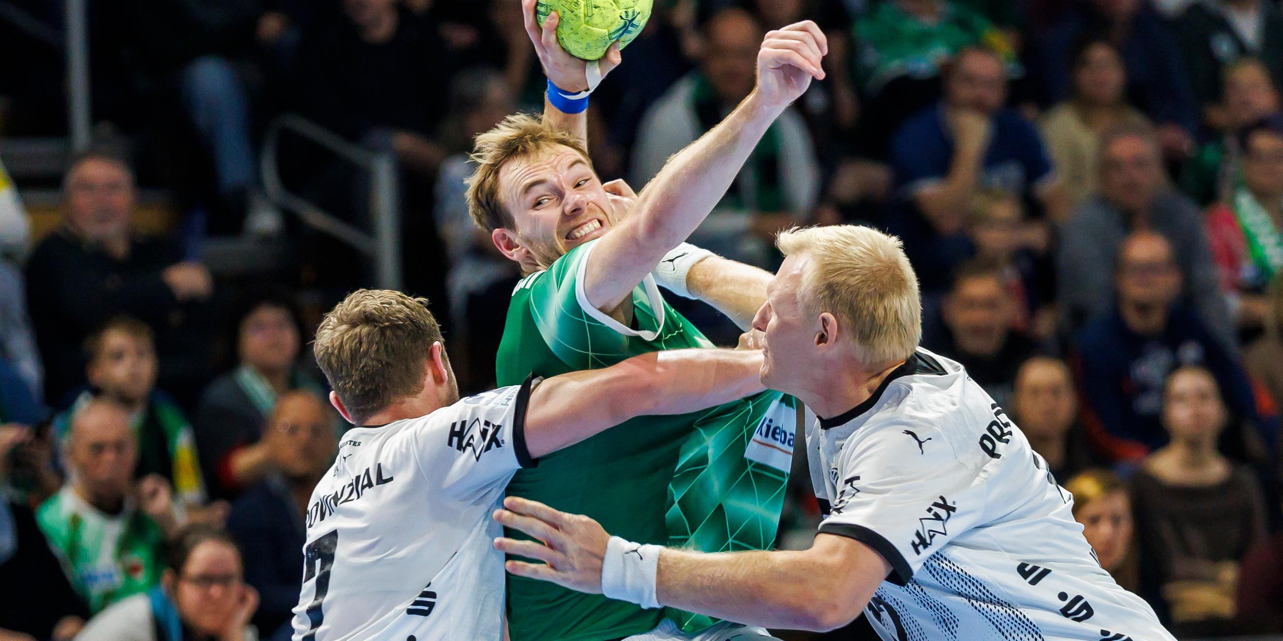 Berlins Mathias Gidsel (M) setzt sich gegen Magnus Landin Jacobsen von THW Kiel (l) und Patrick Wiencek von THW Kiel (r) durch.